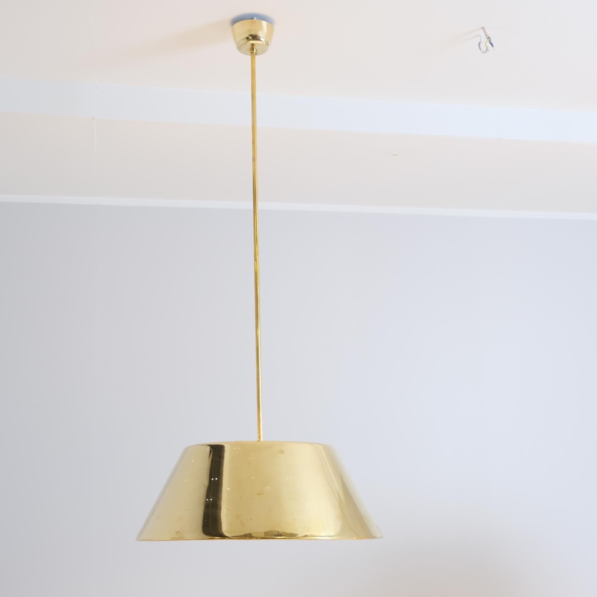 Una grande lampada da soffitto in ottone del maestro dell'illuminazione finlandese Paavo Tynell. Questa grande lampada in ottone ha un diametro di 60 cm ed è notevolmente più grande rispetto ai modelli più comuni di lampade da 40-50 cm. Il pendente
