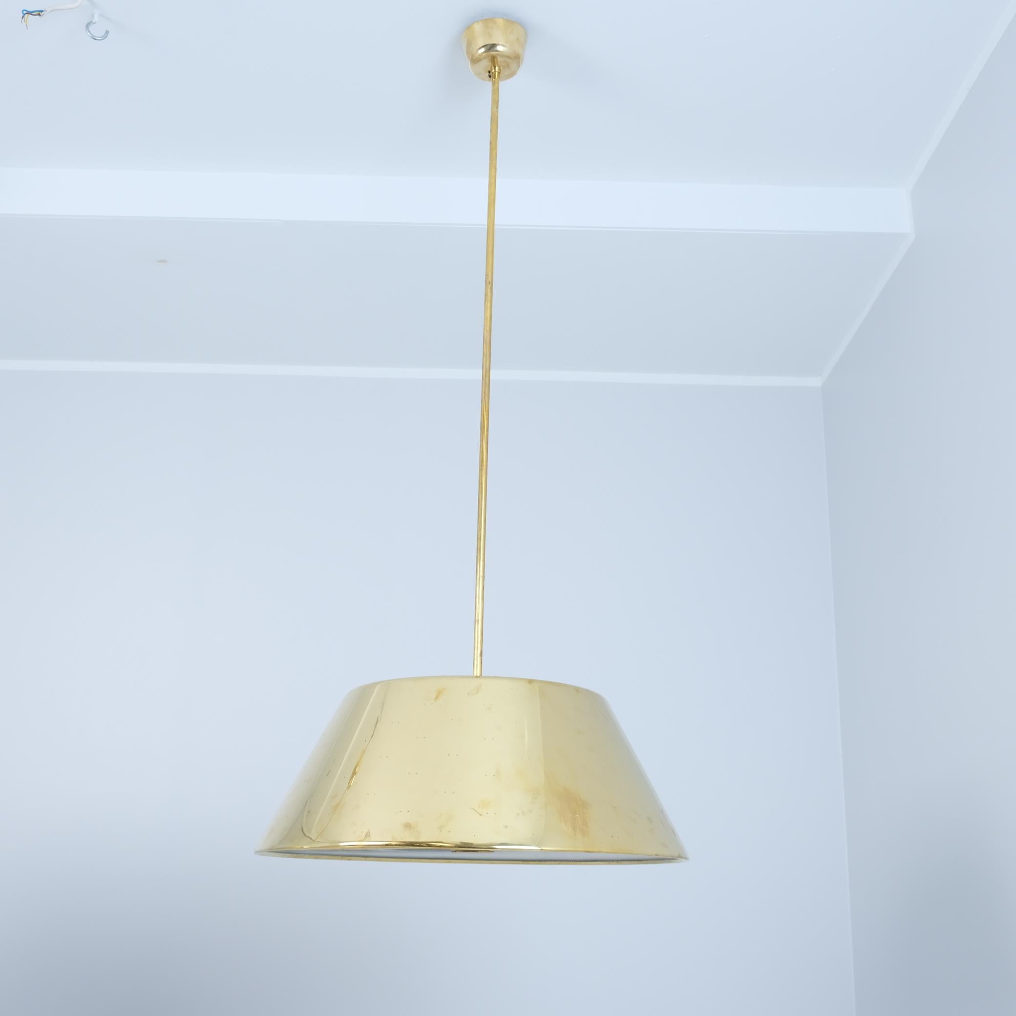 Una grande lampada da soffitto in ottone del maestro dell'illuminazione finlandese Paavo Tynell. Questa grande lampada in ottone ha un diametro di 60 cm ed è notevolmente più grande rispetto ai modelli più comuni di lampade da 40-50 cm. Il pendente