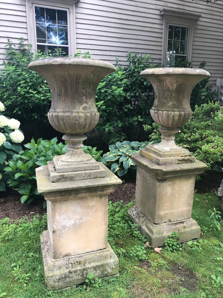 This is one pair of an amazing and stately set of four hand carved campana-form urns with quarter-lobed bodies and plain everted rims on their original tiered plinths. They originally decorated one of the Duke of Marlborough's gardens at Cornbury
