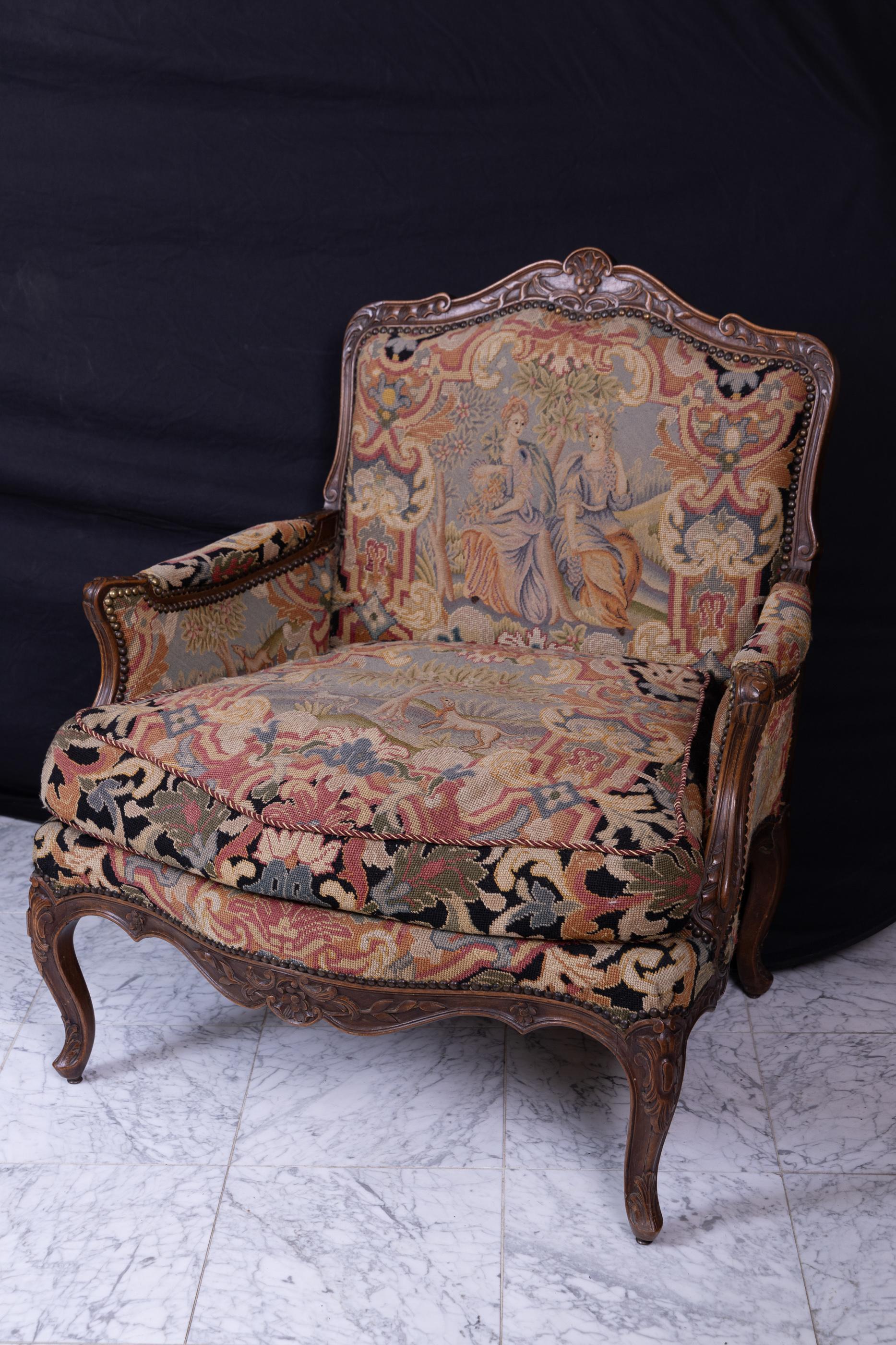 Grand pair of French 18th century Louis XV walnut bergeres, heavily carved on top, arms, apron, and legs; upholstered in the original needlepoint upholstery on the back, sides, the front above the apron, and the cushions. 
