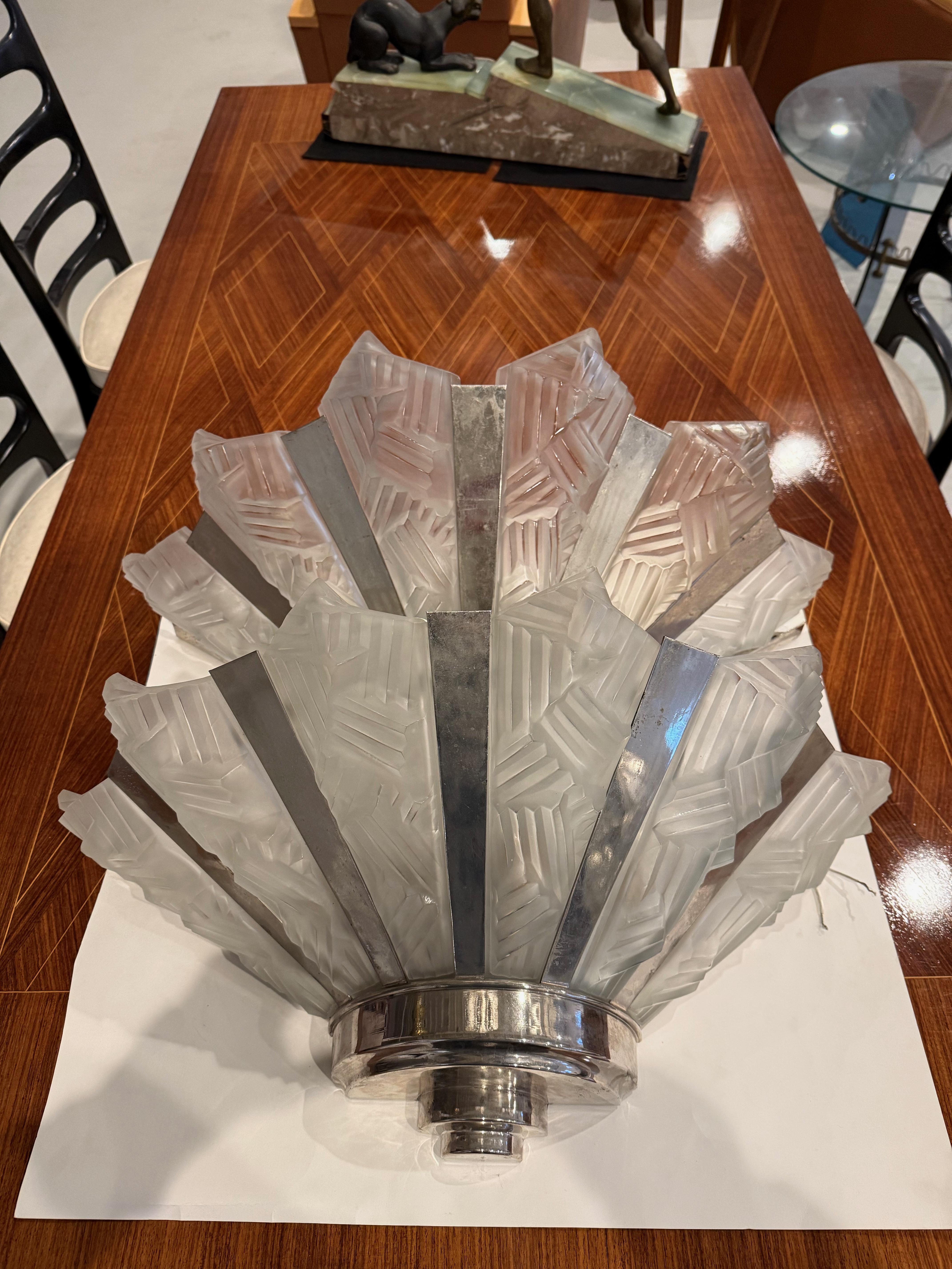 Stunning pair of French Art Deco sconce by Degue. Each sconces has six clear frosted glass shades having intricate geometric motif details throughout. The shades are held by a matching silver geometric design frame. Can be re plated upon request.