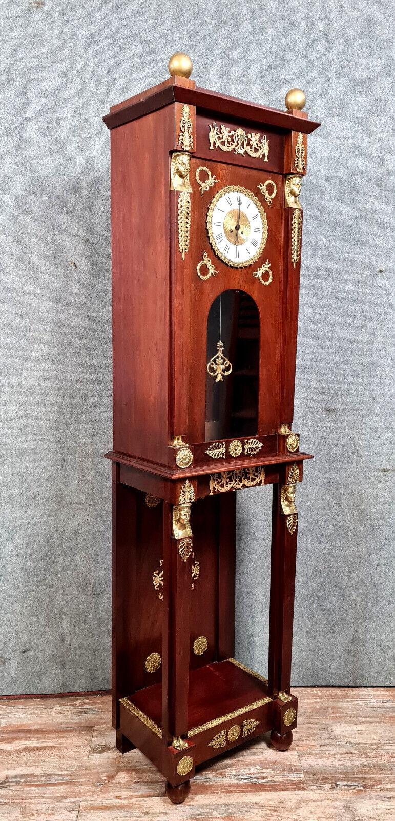 Eleva la decoración de tu hogar con este impresionante reloj regulador de parqué de estilo Imperio, digno de museo, fabricado en lujosa madera de caoba. Esta impresionante pieza, que data aproximadamente de 1880, presenta abundantes ornamentos de