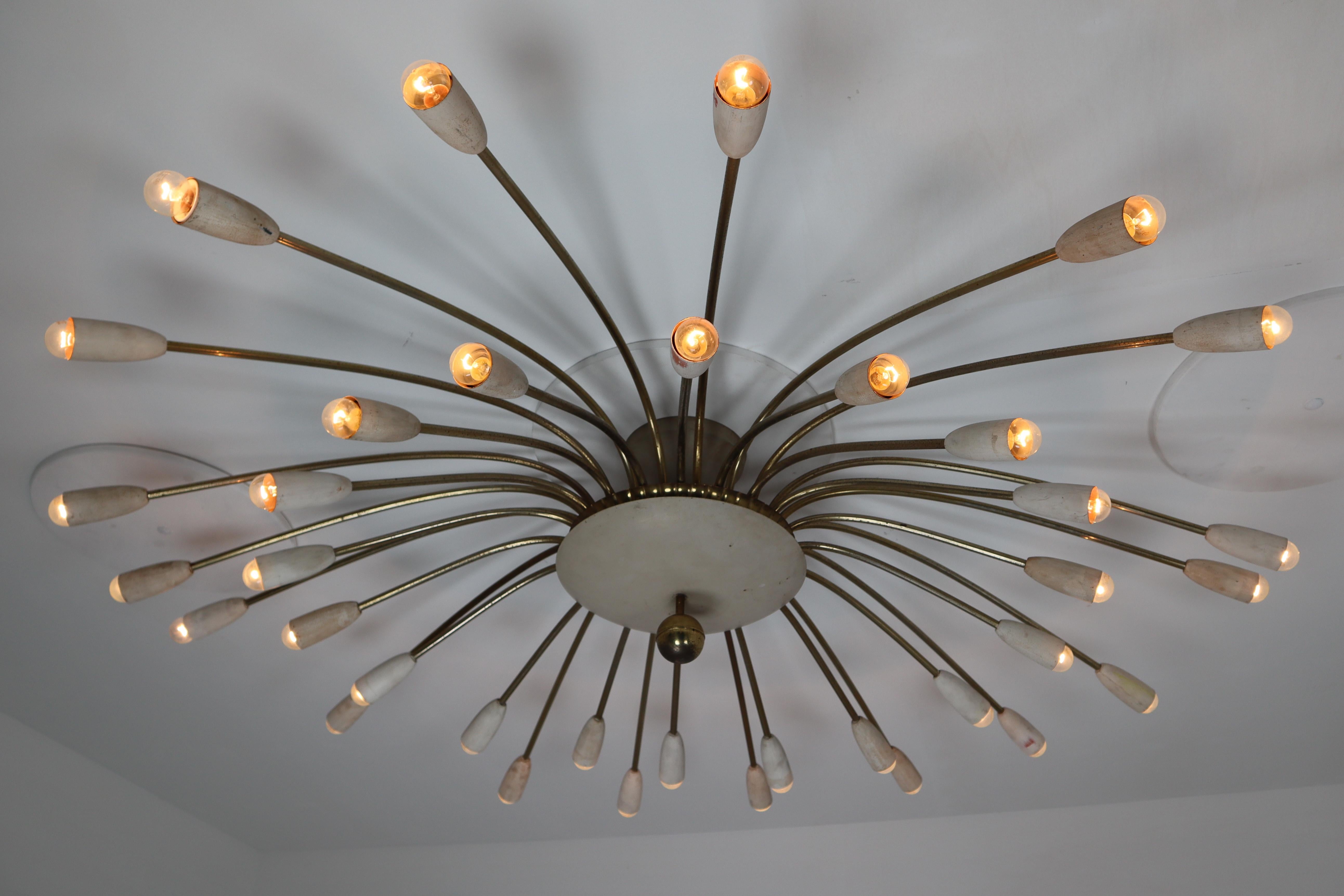 This unique midcentury modernist Sputnik features a sculptural spider form design on a patinated brass frame with accents in brass and of white encased over the (36) lights. It has been newly rewired and is in excellent original patinated condition.