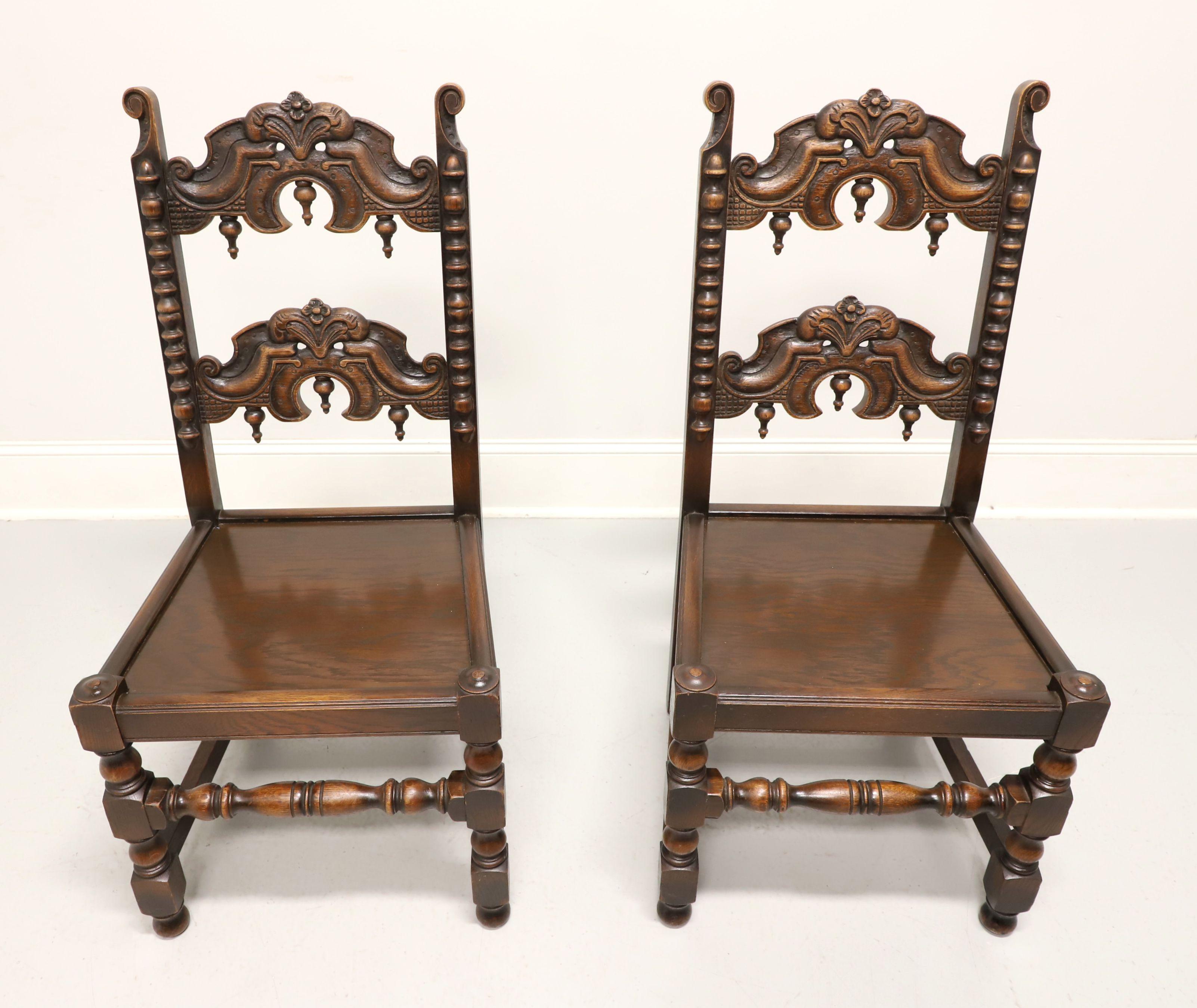 An antique pair of Gothic Revival style dining side chairs by Grand Rapids Bookcase and Chair Company. Solid oak with carved and turned details. Features a decoratively carved ladder back with inverted finials, carved stiles, solid seat, turned