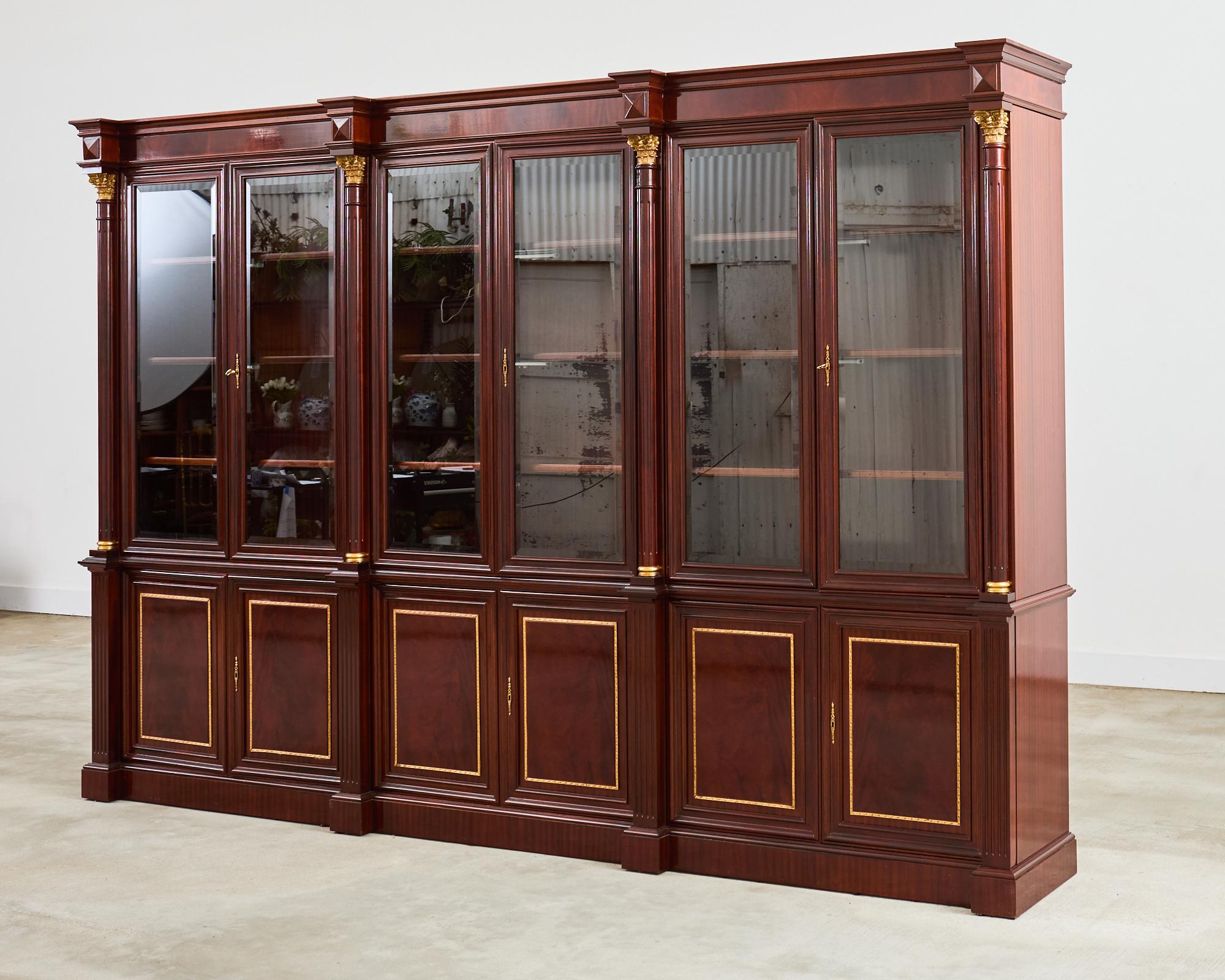Opulento mobile libreria realizzato in mogano secondo il gusto reggenza inglese. La cassa in due parti presenta colonne in stile neoclassico greco-romano nella parte anteriore con montature in bronzo e intricati capitelli corinzi. La parte superiore