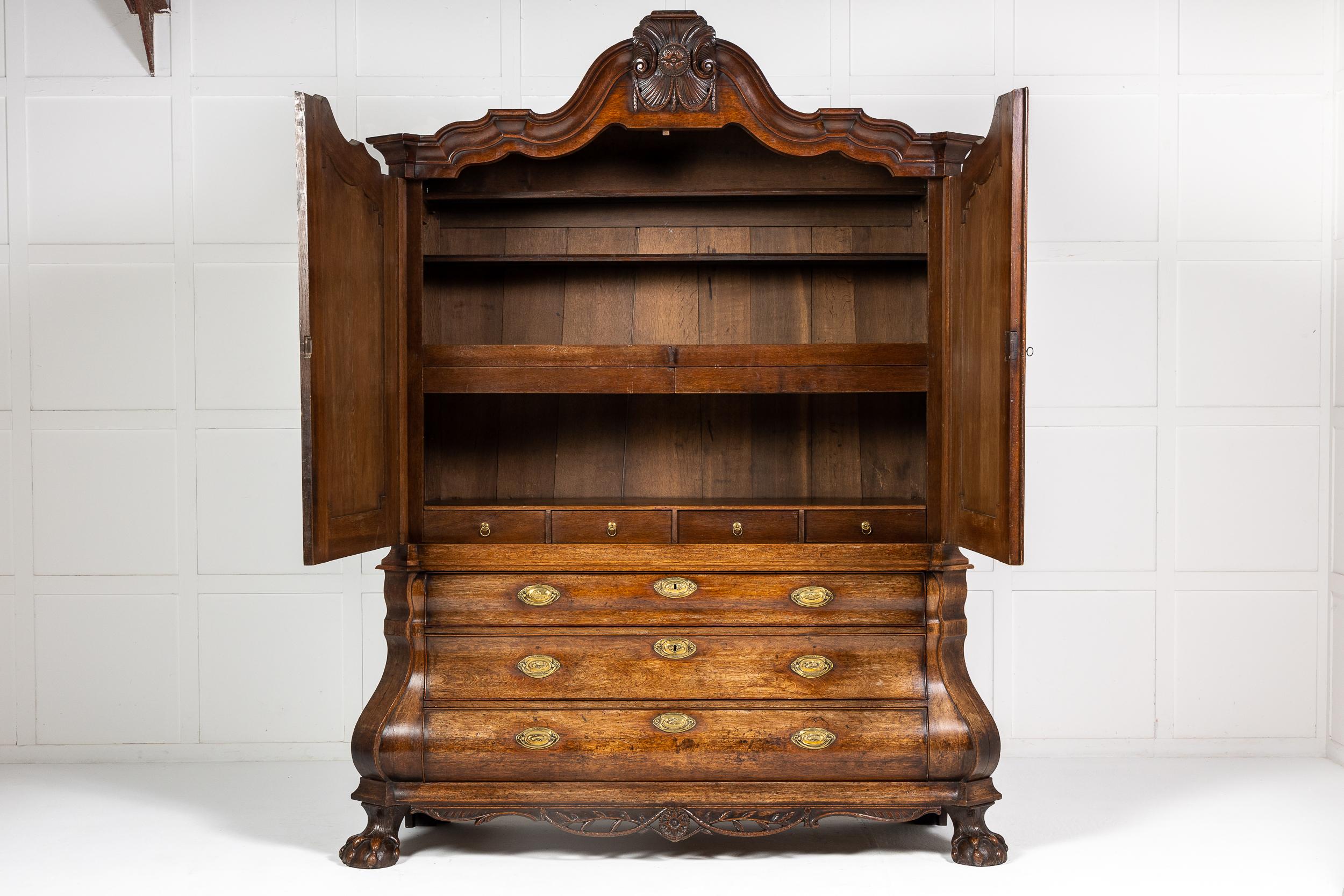 A grand scale 18th century Dutch oak Rococo bombé armoire
having a renowned shaped, wavy cornice with typical hand carved mouldings. The top half of the cabinet has two moulded panel doors with lock and key, which open to reveal a large storage