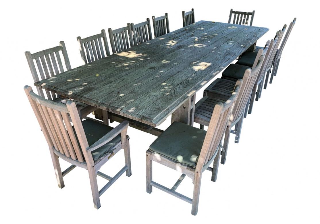 Kingsley Bate teak table with full length double cross stretcher, planked top with beveled edge. Comes with 14 chairs comprised of 2 armchairs and 12 side chairs. The chairs are quite comfortable and the overall condition is very good. Desirable
