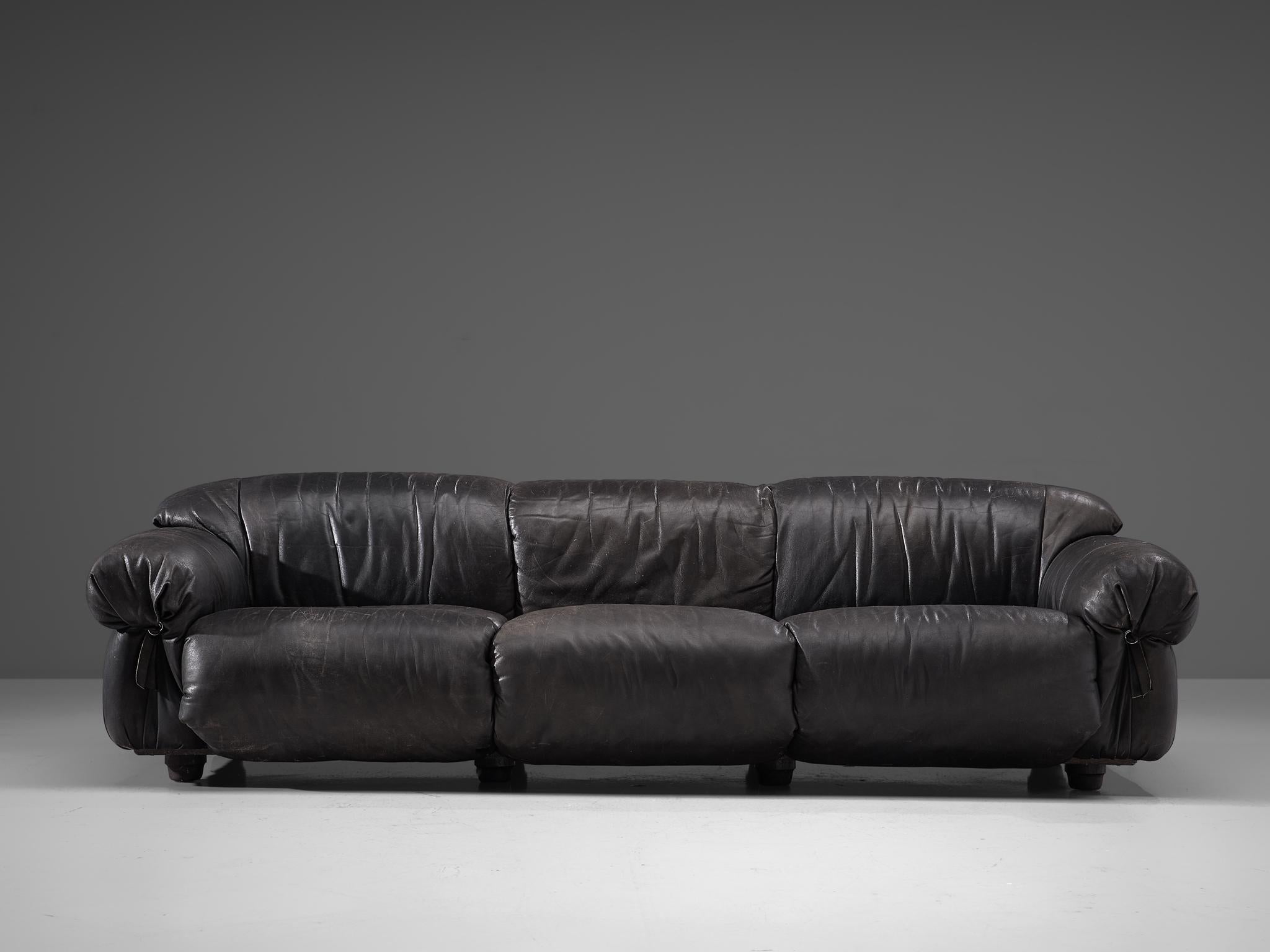 Three-seat sofa, leather, Italy, 1970s.

Grand and bulky three seat sofa. Completely covered in high quality, thick leather that patinated beautiful over the years. The draped and folded leather is finished with leather straps at the front of the