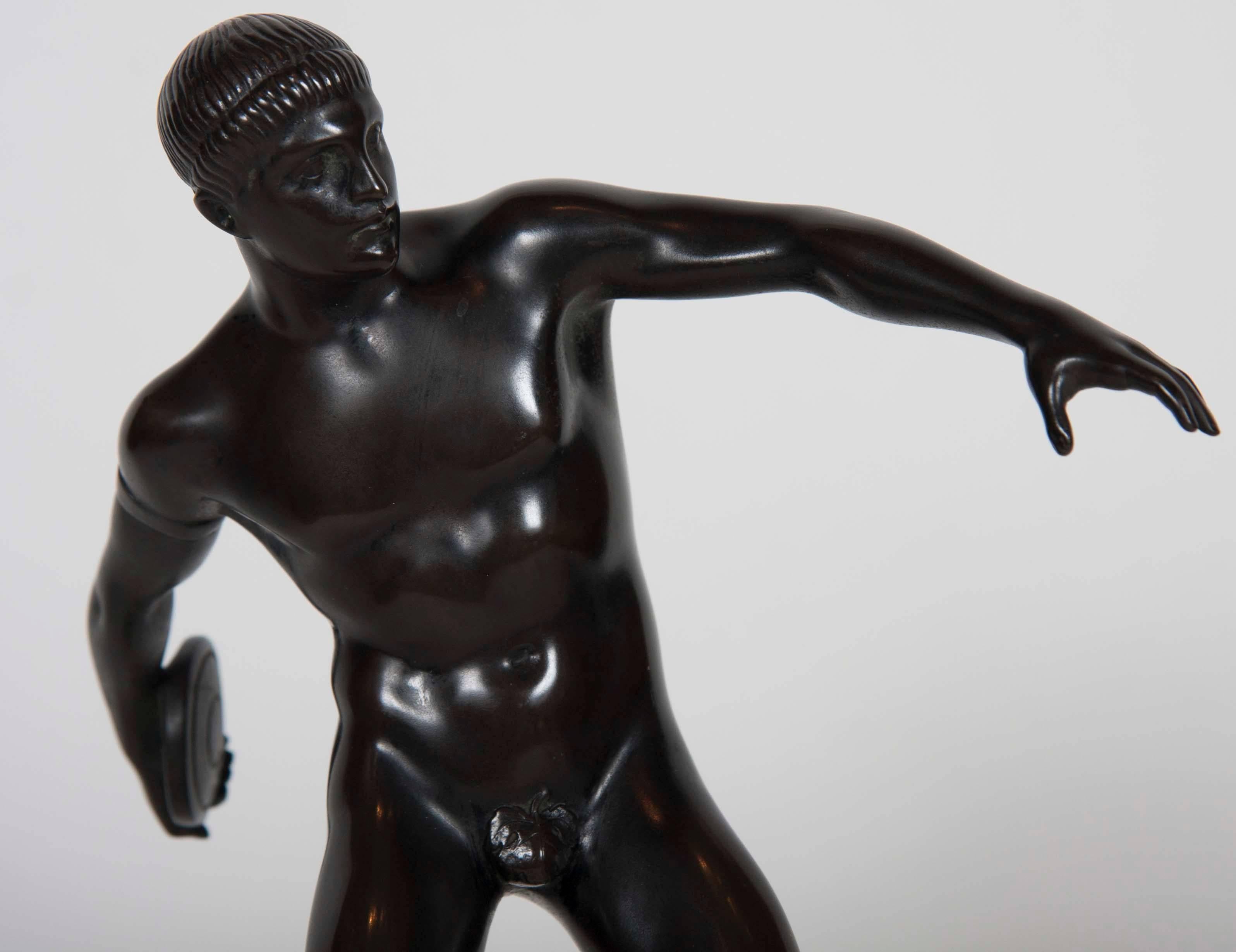 A Grand Tour patinated bronze figure of a discus thrower mounted on a marble base.