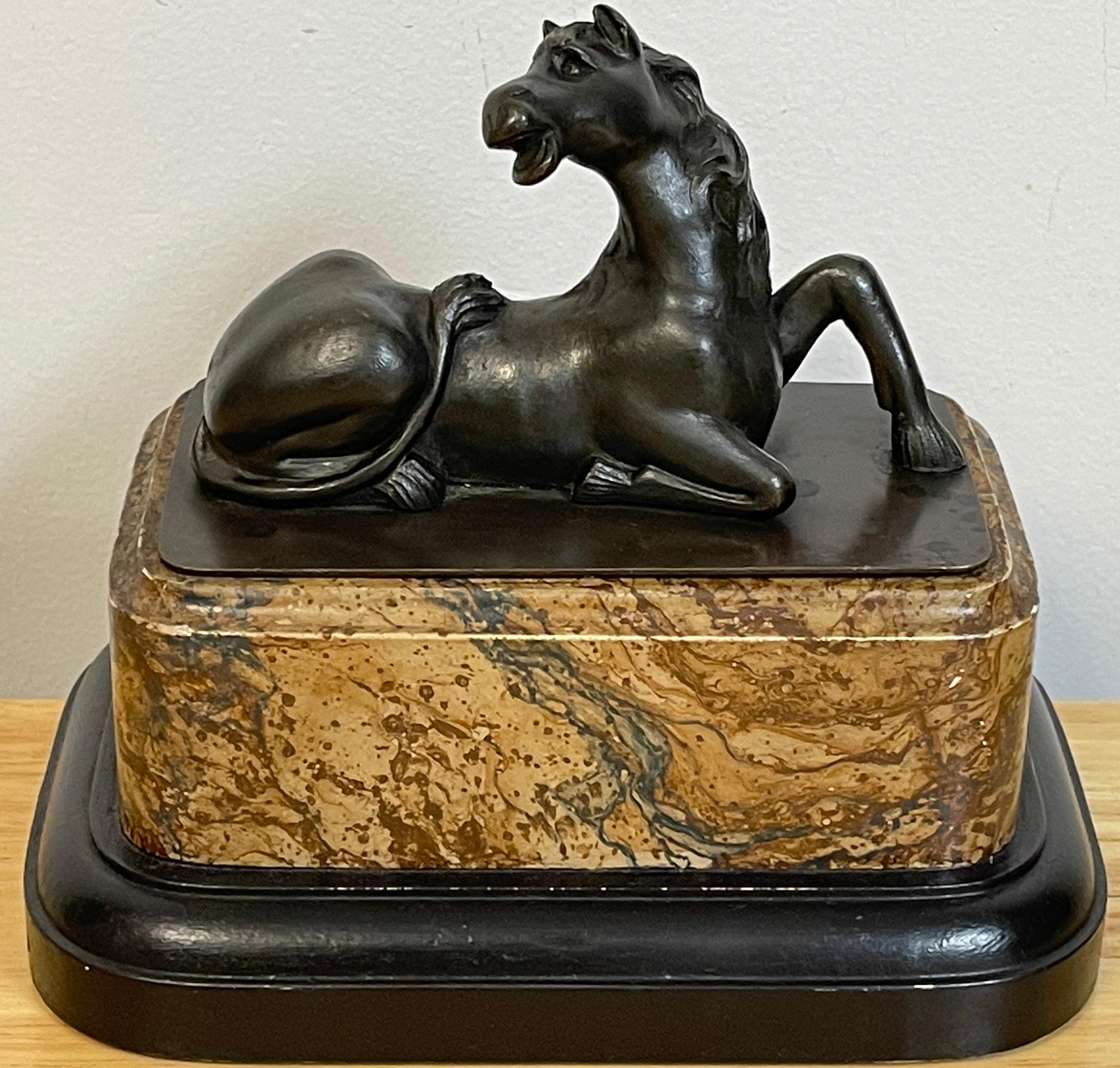 Grand Tour Bronzemodell eines liegenden Pferdes, realistisch gegossen und modelliert, erhöht auf einem unechten marmorierten Sockel.
 