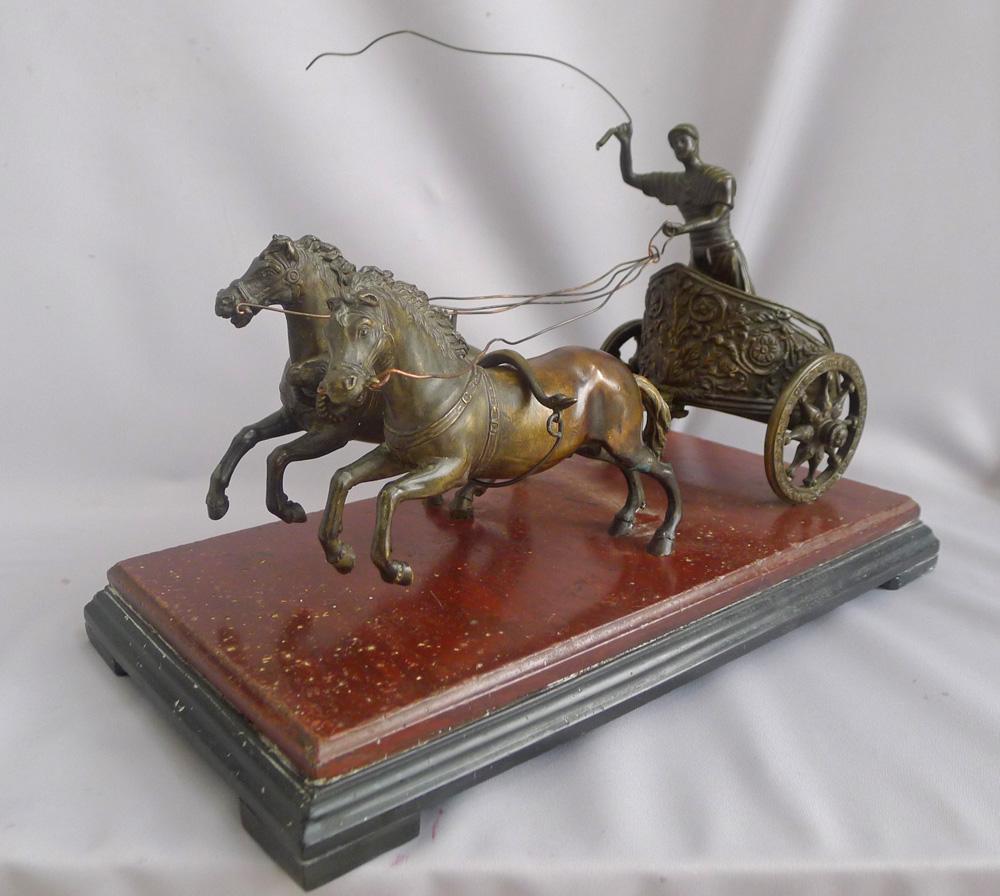 A fine Italian Grand Tour two horse racing chariot driven at full pelt by the charioteer. The two horses with full rig and yokes over their backs. Between them a profusely decorated shaft terminating in a ram's head. The two wheeled chariot highly