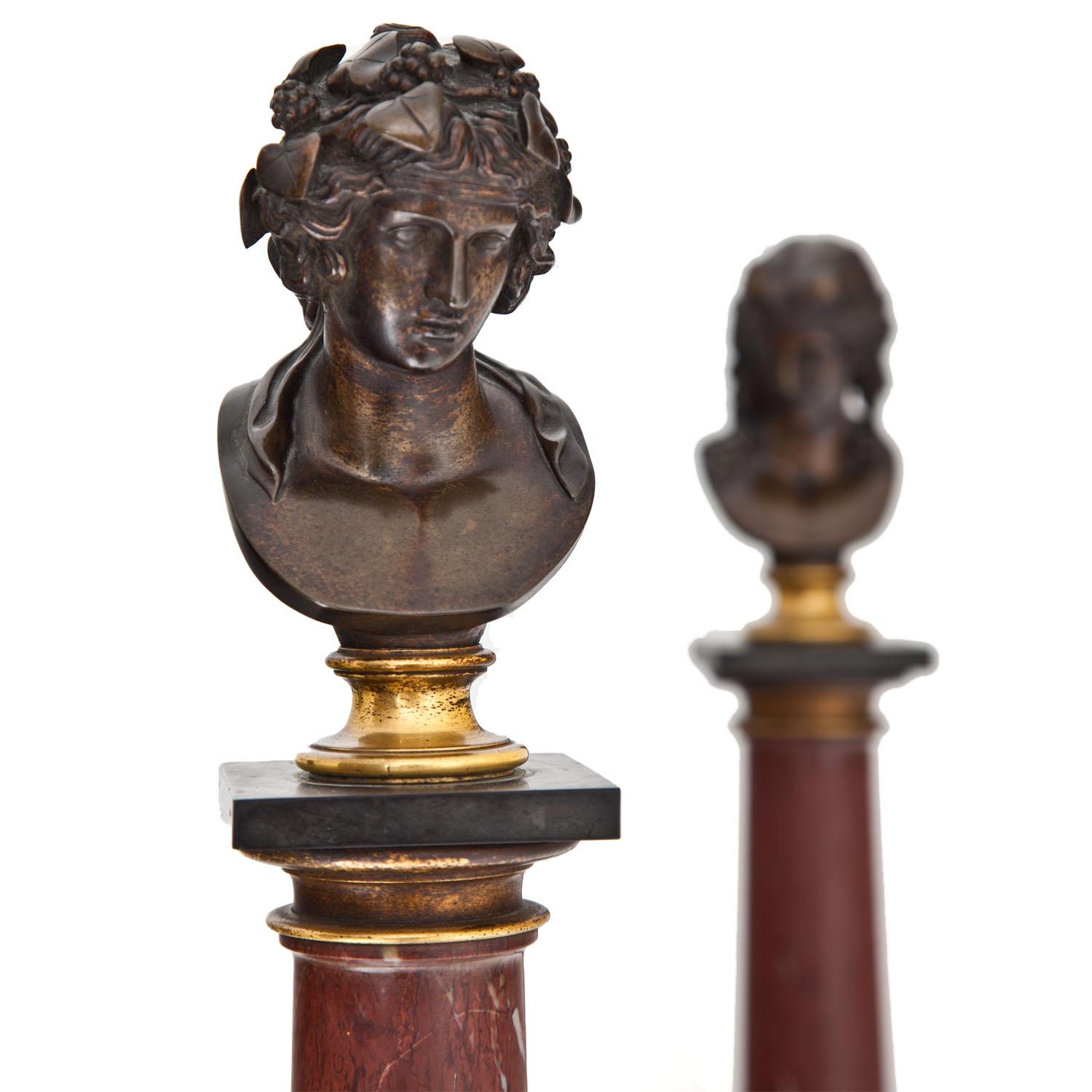 Pair of bronze busts as grand tour objects of the youthful antinous as dionysus after the Lansdowne type and Dionysus with vines in his hair (also known as Ariadne, Capitoline Museums). He is stamped on the back GS with bee for George Emil Henry