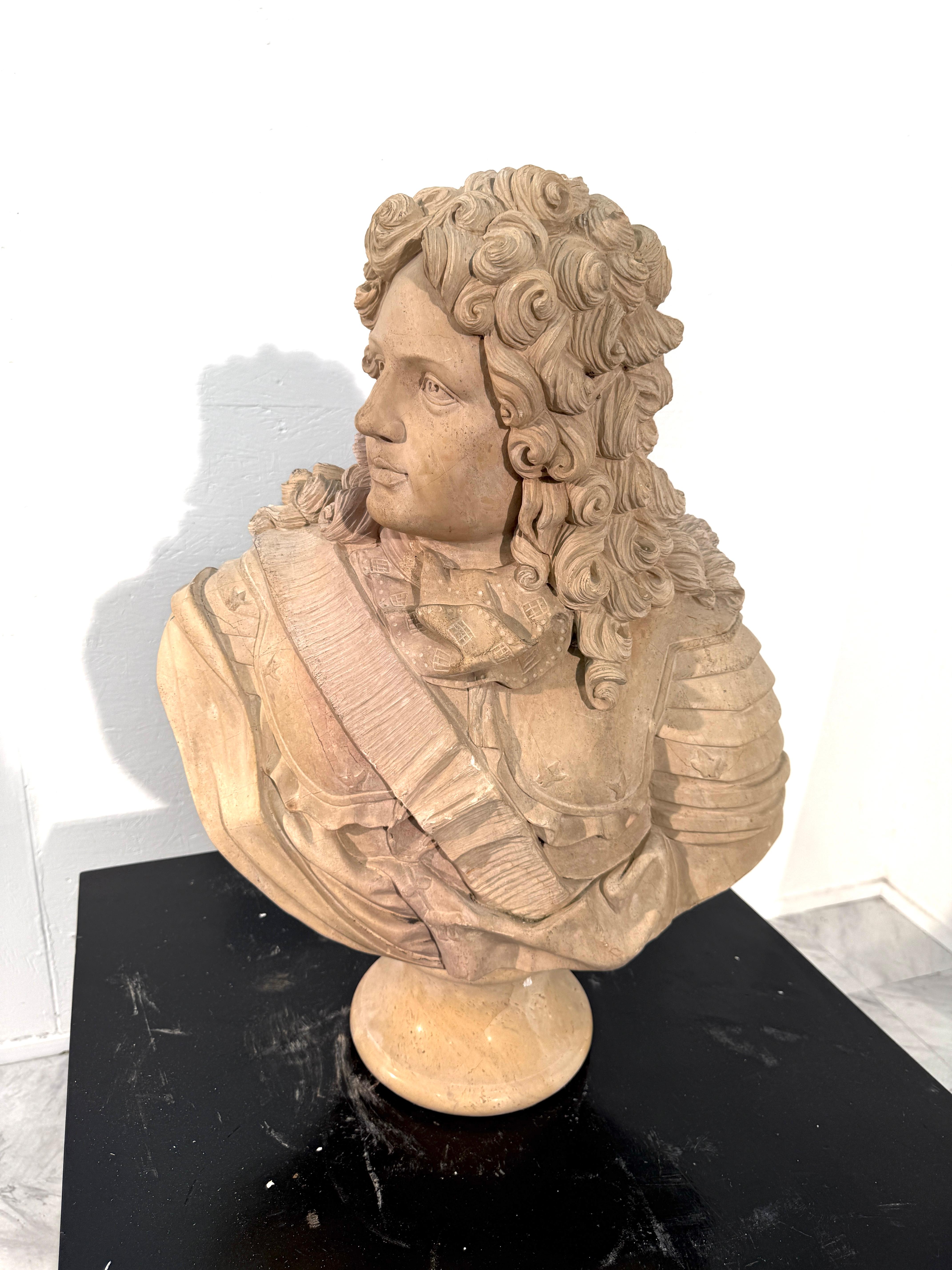 An elegant 19th-century Italian marble bust, finely carved during the Grand Tour period. The sculpture portrays Louis XIV in period attire, with a sash draped across his chest and meticulously detailed curls cascading around his face. The artisan’s