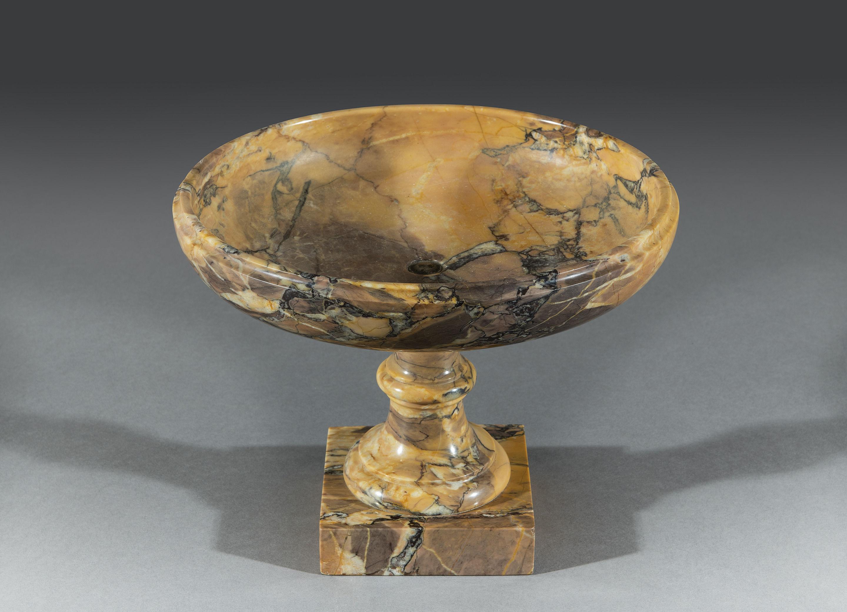The Sienna marble Tazza has a striking vein of color flowing the through the entire ornament. The shallow dish is carved with a thumbnail molded edge and stands on a turned column supported on Socle plinth base. 

'Broccatello di Siena' (Convent