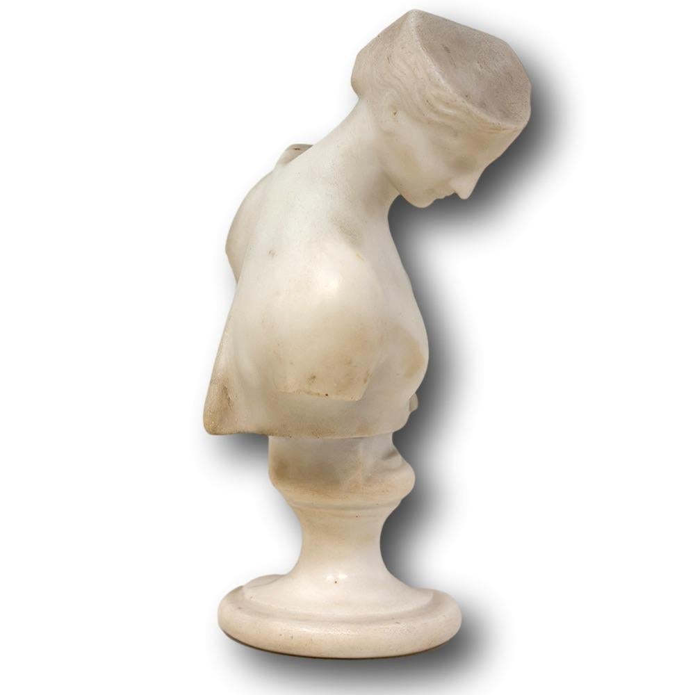 Fine marble bust on pedestal after the antique. The bust sculpted as the goddess Psyche Of Capua presented as a nude female with a draped partial robe having curly hair posing with her head looking left. The bust upon a turned pedestal with circular