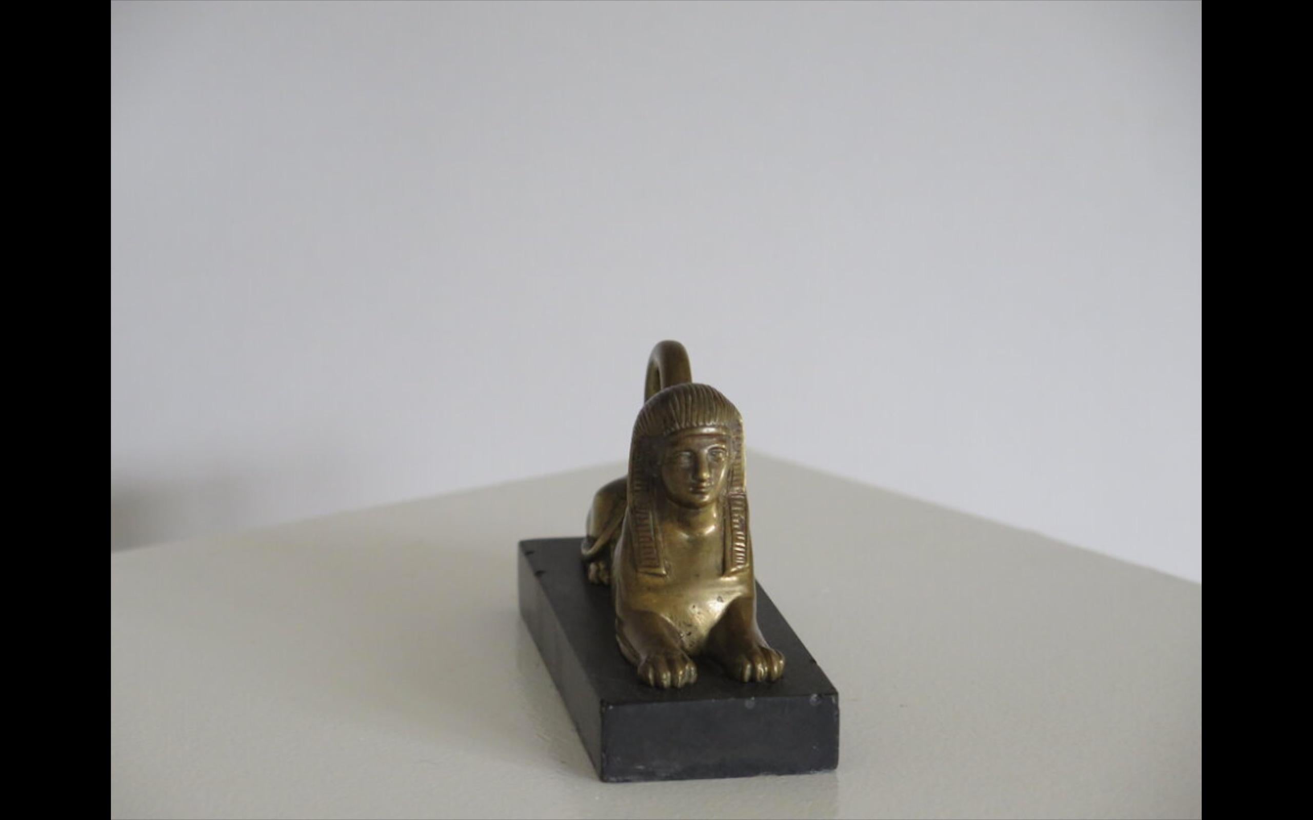 Grand Tour Statue of a Sphinx in Brass or Bronze on Black Marble Base. England, circa 1930. A beautiful piece dating from the 1930s when Egyptomania and Egyptian Revival decoration took over England and Europe.