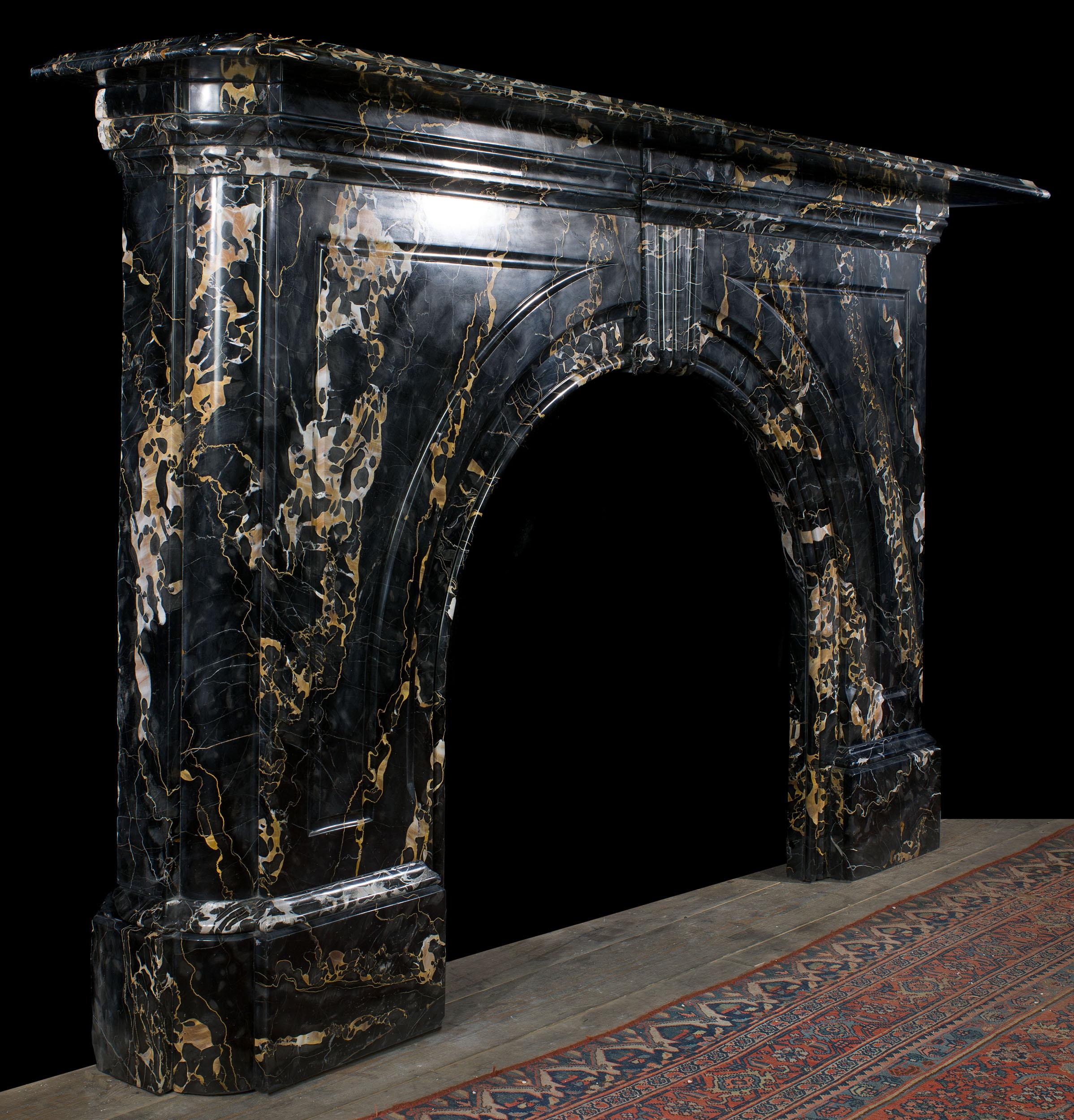 A monumental Victorian arch fireplace in dramatically veined Portoro marble. Striking in its simplicity, the fireplace is centered by a keystone and the arch is framed by two boldly carved spandrels.
English, c.1860.

Notes: Varieties of Portoro