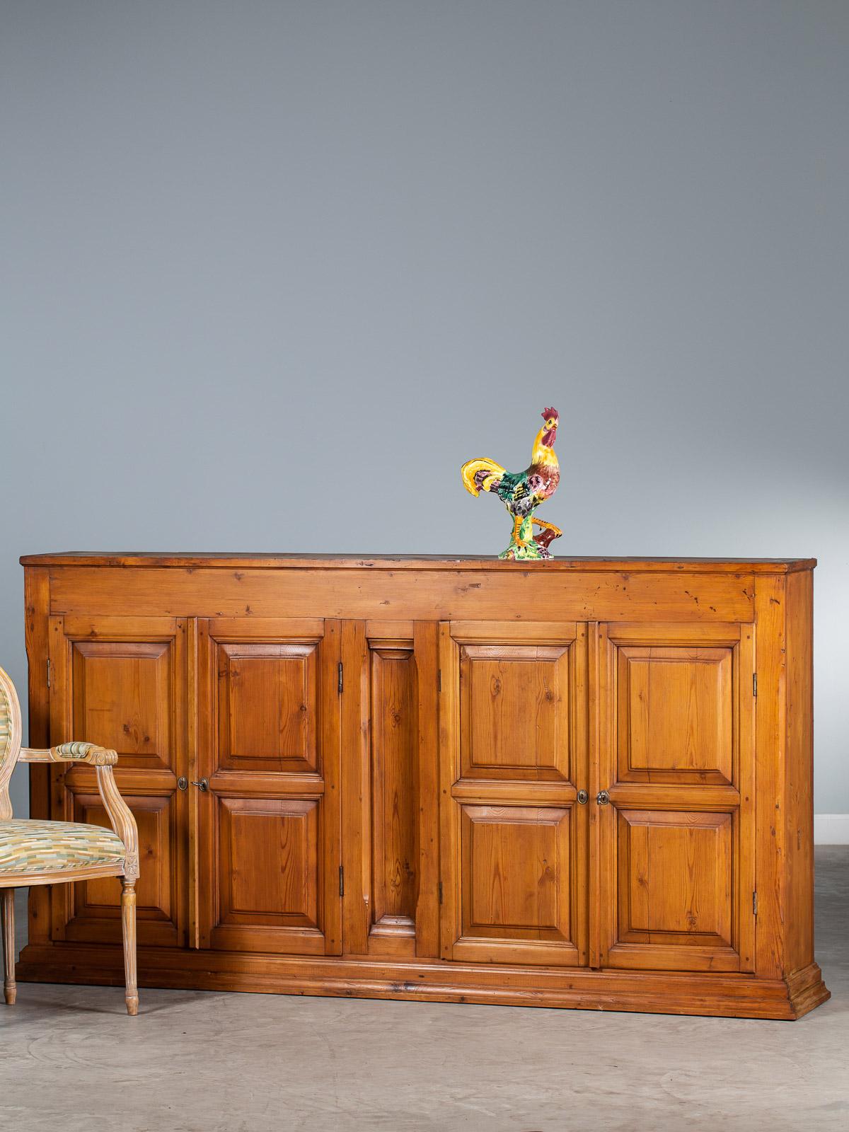 This vintage French solid pine buffet credenza cabinet circa 1930 features four cabinet doors made of deeply recessed panels and molding. Heavy and substantial this piece was originally a shop fitting for a retail establishment for the storage of