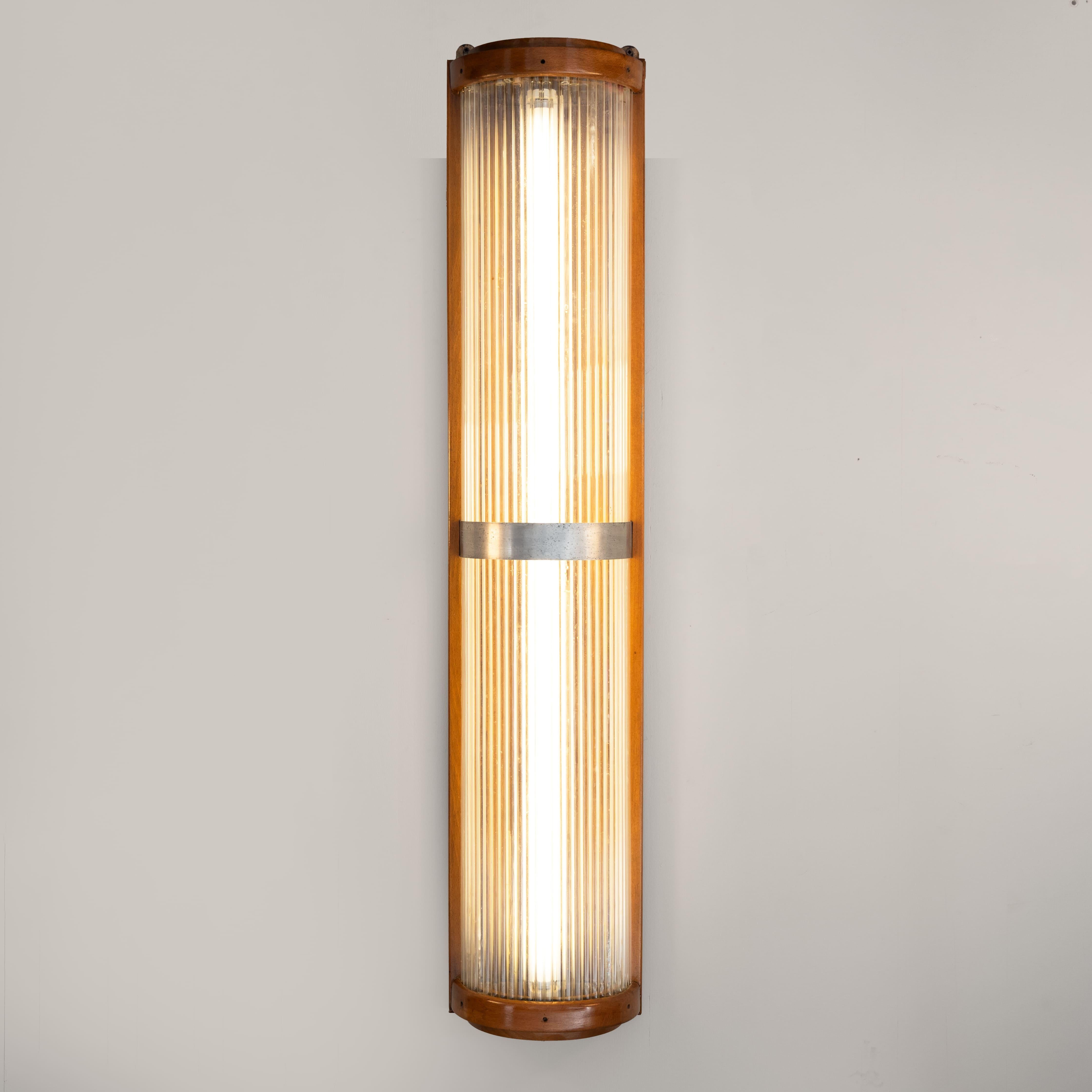 Aplique grande, fabricado en los años 30 en estilo Art Déco. Estructura de madera y metal cromado con elementos verticales de varillas de vidrio transparente, dispuestos en secuencia para crear un efecto de iluminación escenográfico.

Buen estado