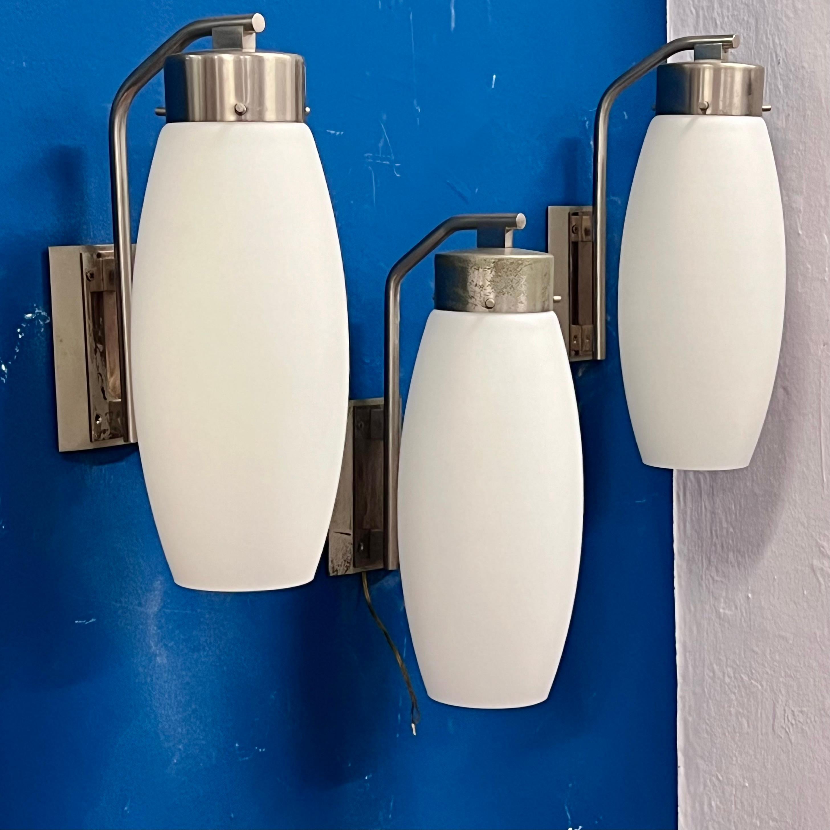 There are three of them, they are big and they are perfect. Purchasable separately.
A series of three Stilnovo-branded wall sconces, branded recessed into the plates of the wall brackets.
Made of nickel-plated brass and frosted glass. A large