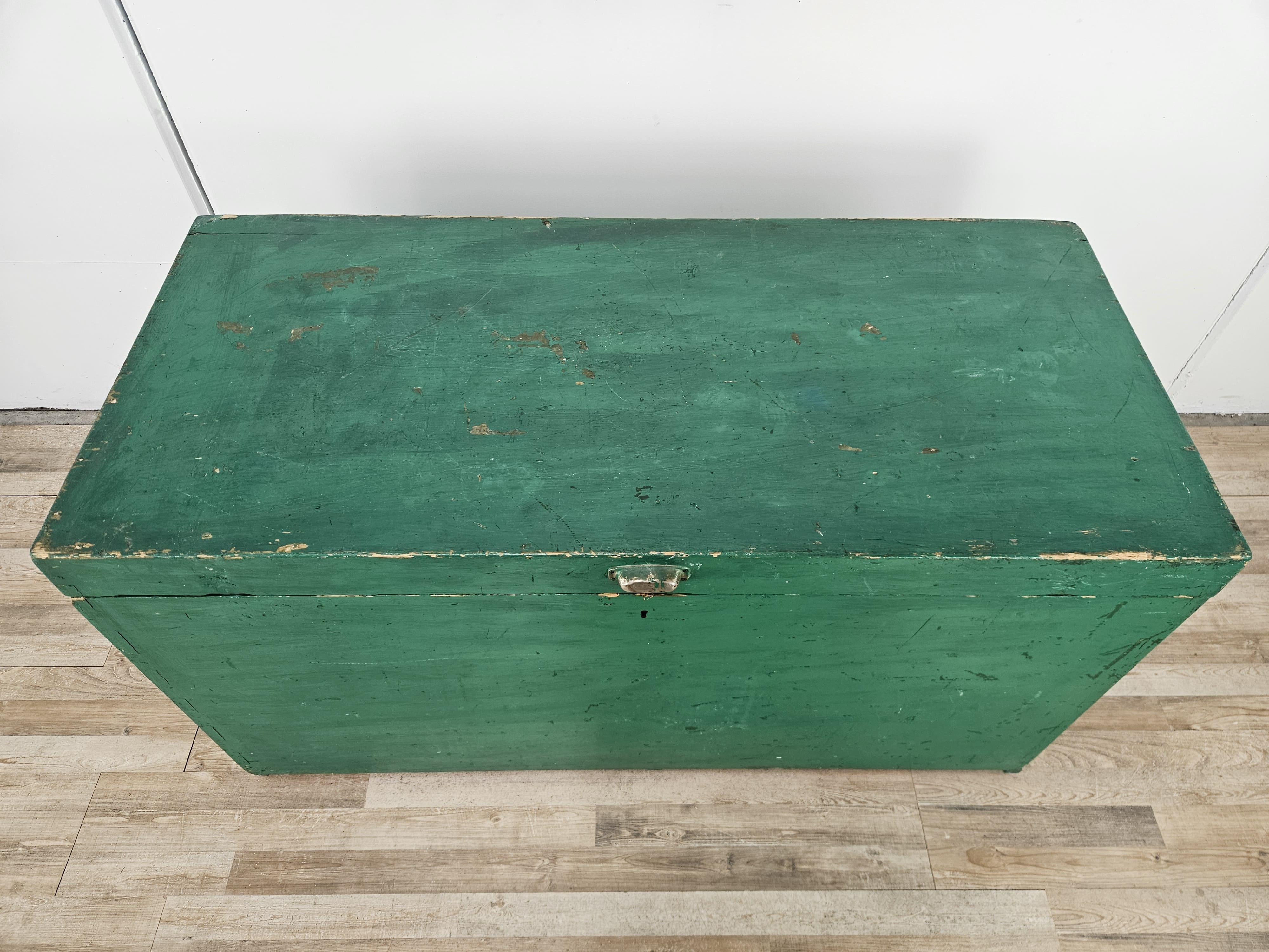 Grande baule in legno dipinto verde con maniglie laterali per facilitarne il trasporto e chiusura in ferro battuto.