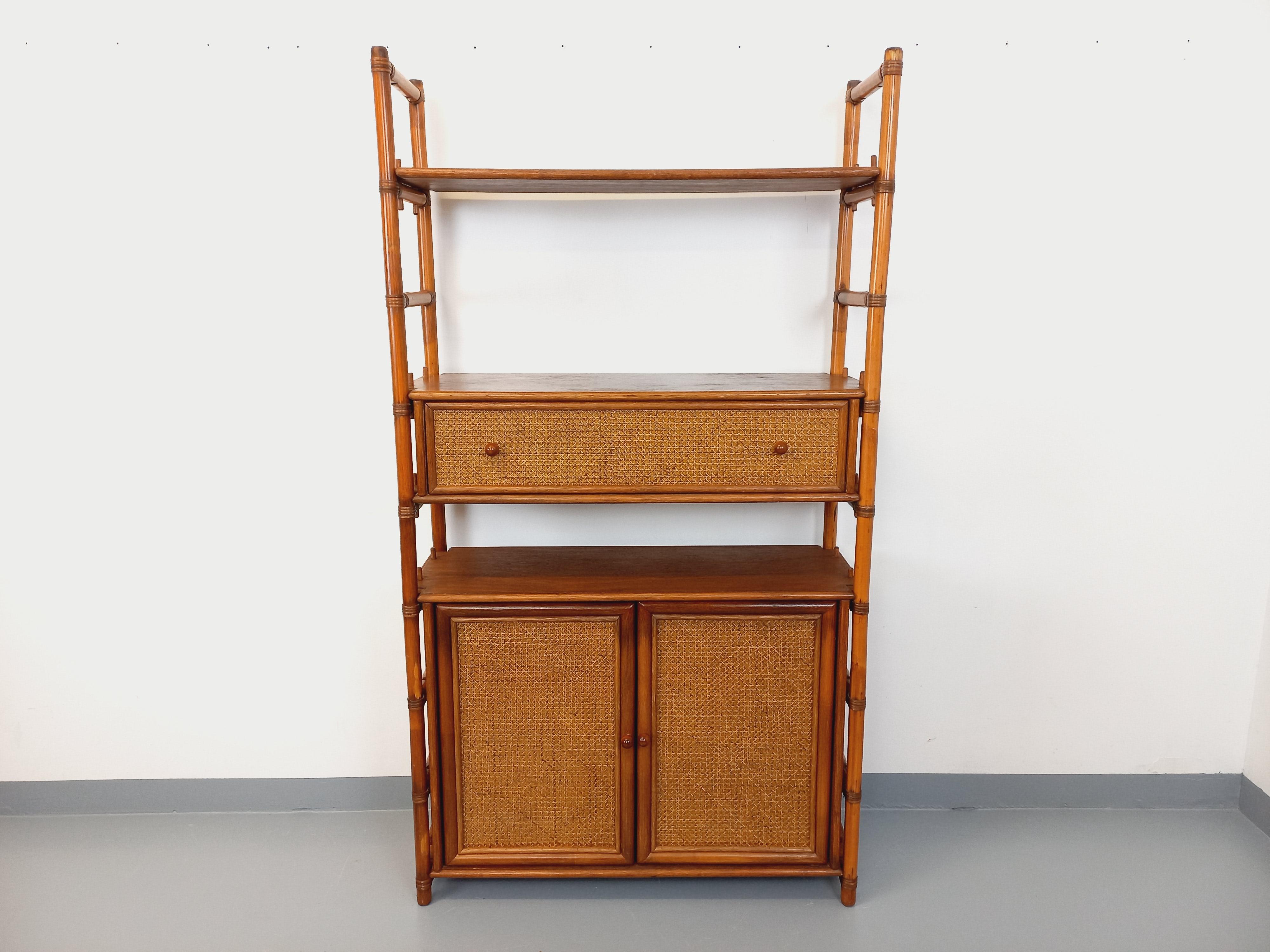 Grande bibliothèque étagère vintage des années 70, en rotin, jolies façades en bois et cannage, 3 étagères ouvertes, 1 grand tiroir, 1 module 2 portes avec une étagère intérieure. La bibliothèque può essere utilizzata al centro di una pièce (le dos