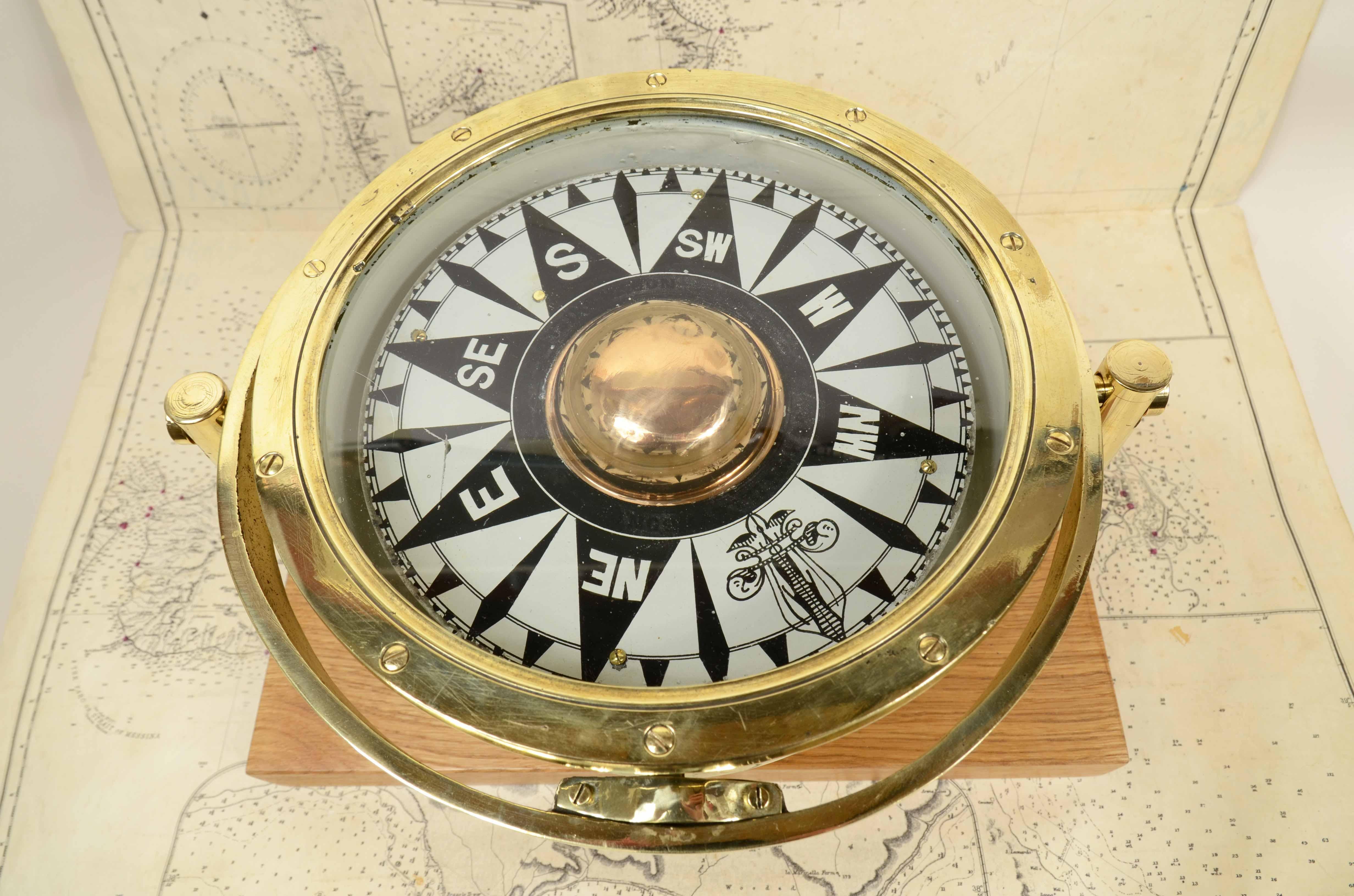 Large brass and glass nautical magnetic compass from the early 1900s, mounted on custom-made oak and brass board. Compass diameter cm 24.5 - inch 9.4, height with base cm 21 - inch 8.3, table width cm 36 - inch 14.2. Good condition, small crack on