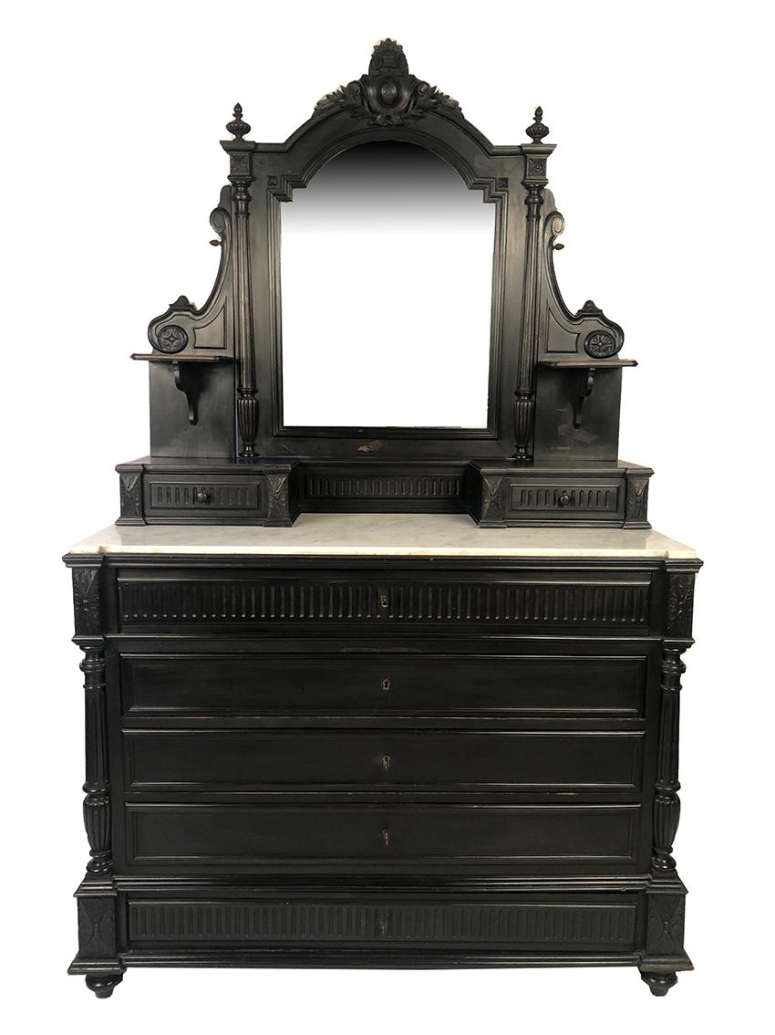 Grande commode psyché en bois noirci Napoléon III
Miroir biseauté, cintré et basculant surmonté d'un cartouche
Plateau de marbre blanc à ressaut.
La partie haute est munie de deux tablettes et deux tiroirs à façade cannelée,
ornée de colonnes