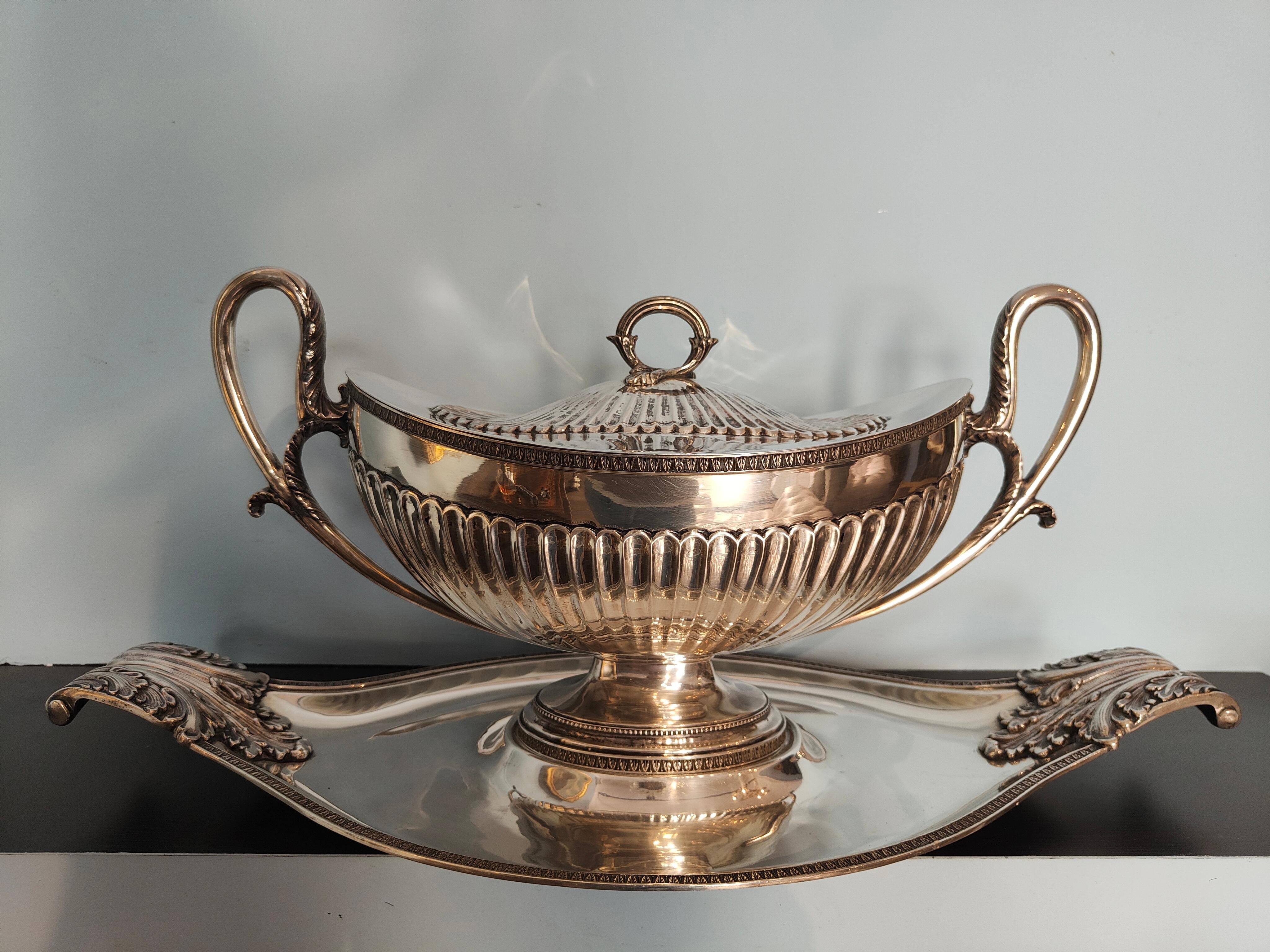 Large and elegant silver soup tureen/centerpiece with oval lid, baccellata with looped sockets on plate with sockets and acanthus leaves.
The object lends itself to various functions: for purely ornamental use, to enrich a table; as a container for