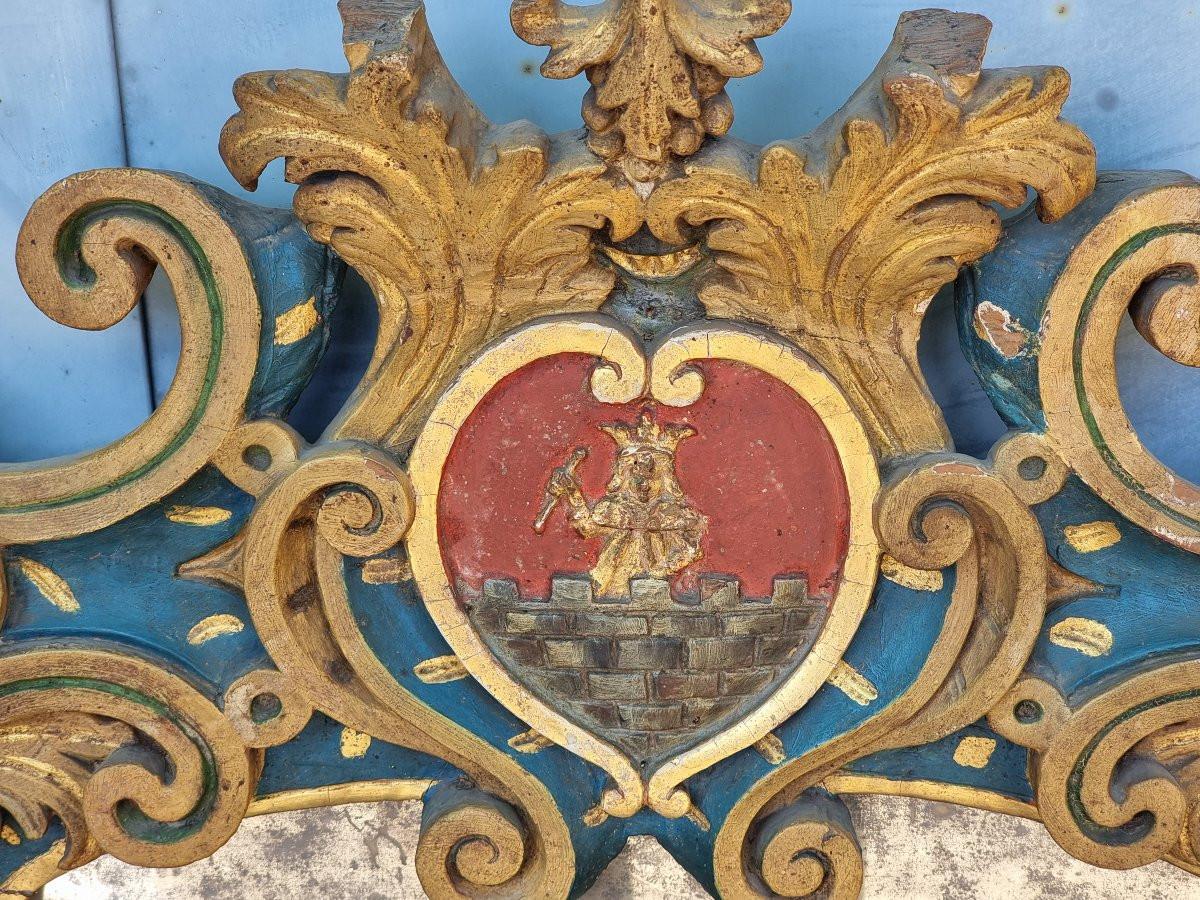 Suggestivo fregio decorativo proveniente dall’area veneta o veneto-emiliana, databile al XVIII secolo. Interamente intagliato a mano in legno massello, presenta una decorazione policroma laccata in blu e verde con ricche lumeggiature dorate,