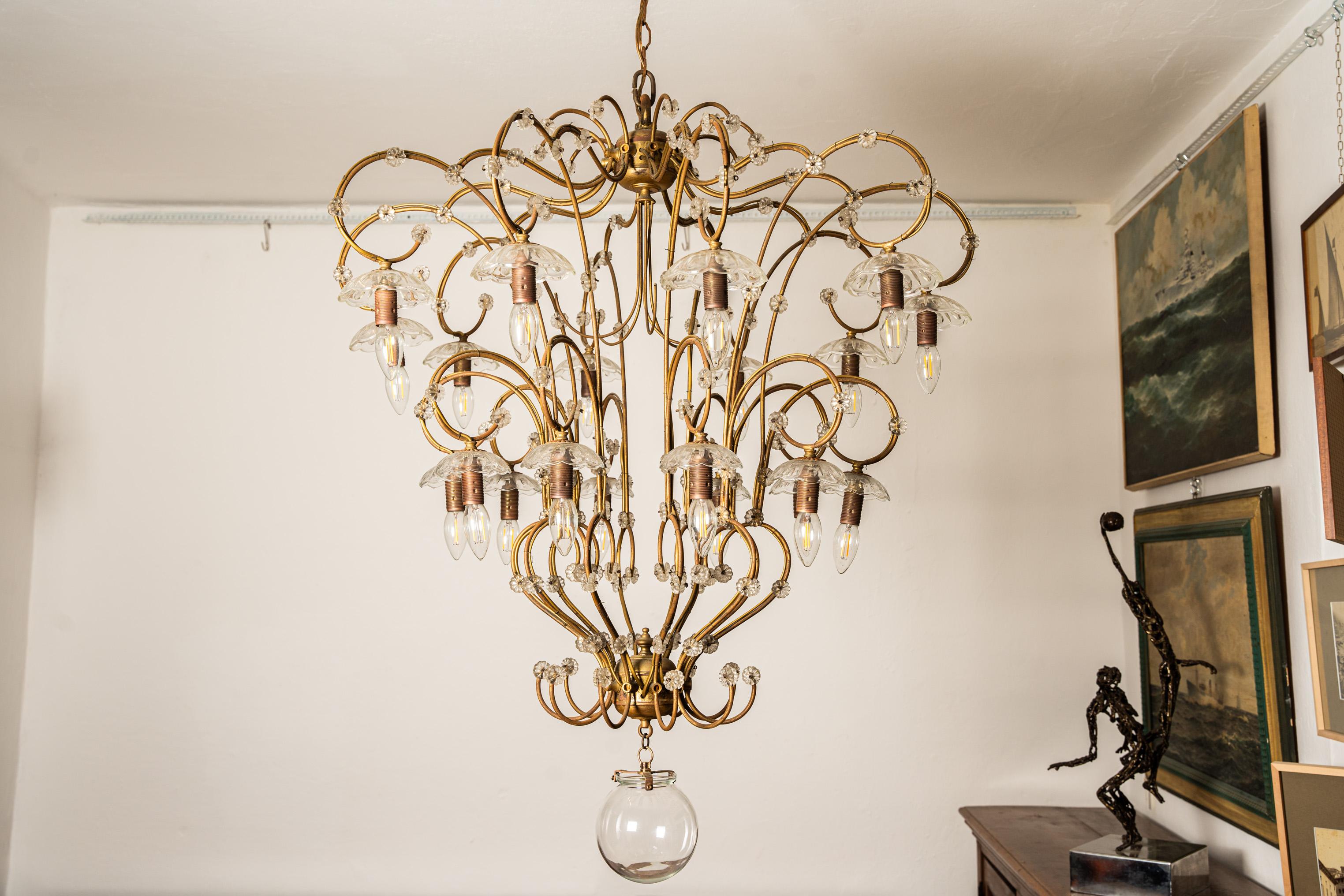 Un important lustre éclectique en laiton et cristal, avec 10 bras et 20 lumières, est une réinterprétation du lustre classique traditionnel, avec la particularité d'avoir les feux de bougies avec leurs soucoupes de verre respectives inversées par