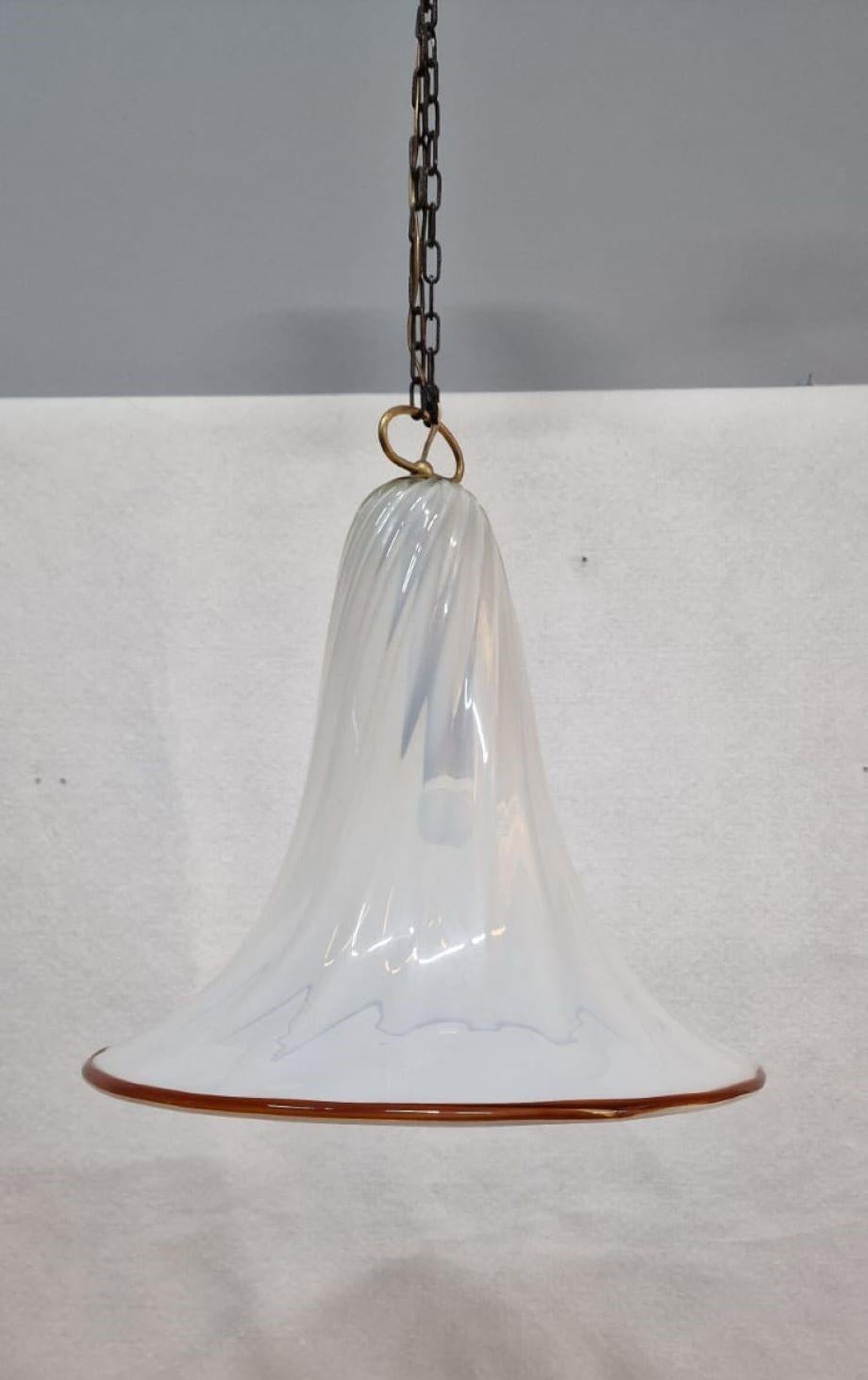Large Murano glass chandelier in the shape of a bell. The chandelier is semi-transparent white with a colored bottom edge. The chandelier is made entirely of glass with a metal hook. 1960s approx.