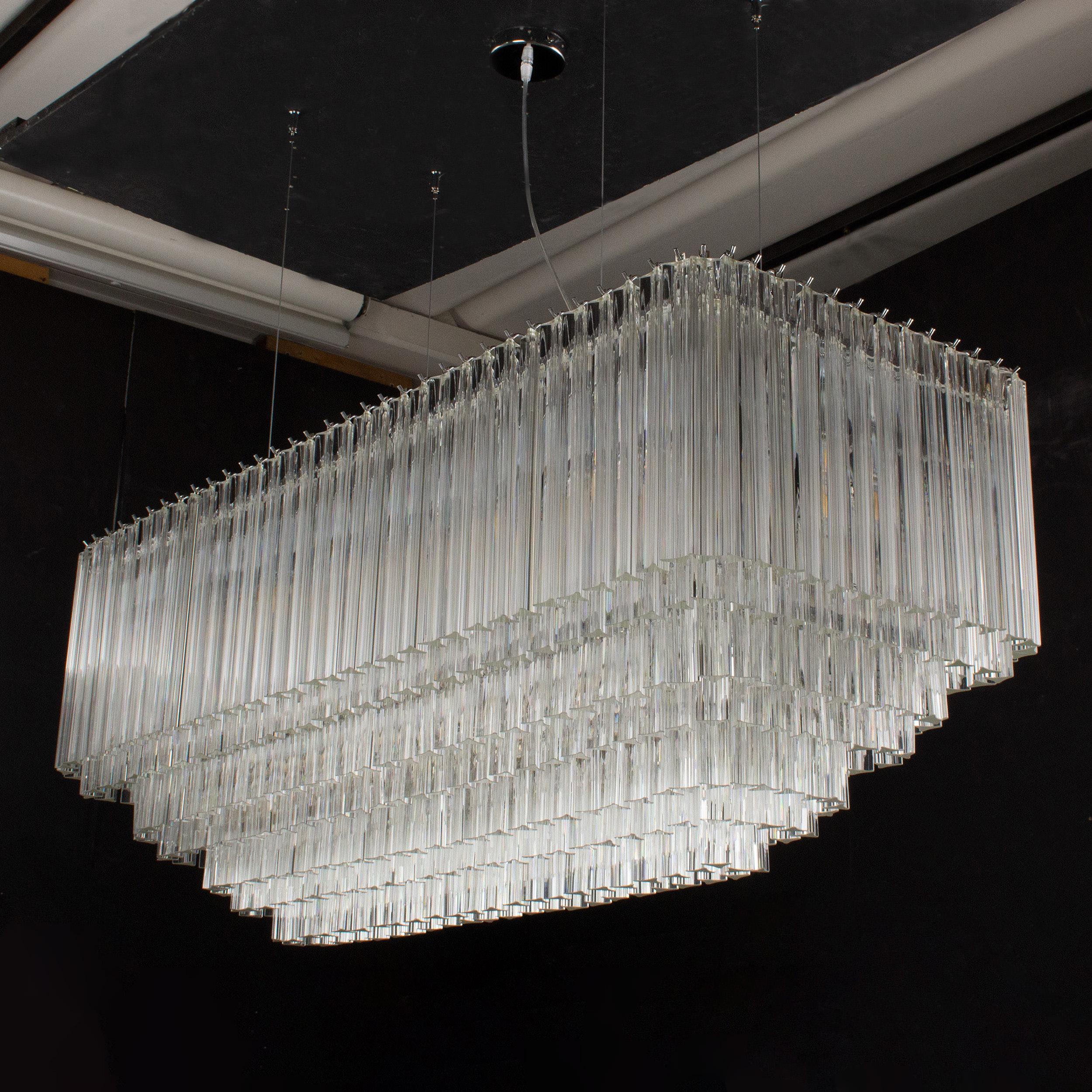 Grande lampadario sospensione con triedri in vetro di Murano ispirato al mid-century italiano.

Direttamente dalla fonte:
Non siamo semplici rivenditori, ma produttori diretti! Situati vicino a Venezia, nel cuore dell'industria vetraria di Murano,