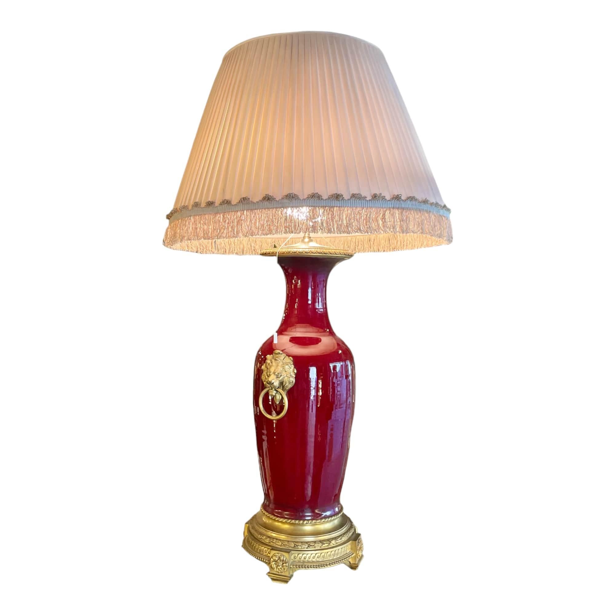 This magnificent “Blood of Ox” porcelain lamp with its bronze frame with lion heads is a true piece of art from the mid-20th century. Its elegant and timeless design makes it a stunning antique designed around 1900. The painstaking details of this