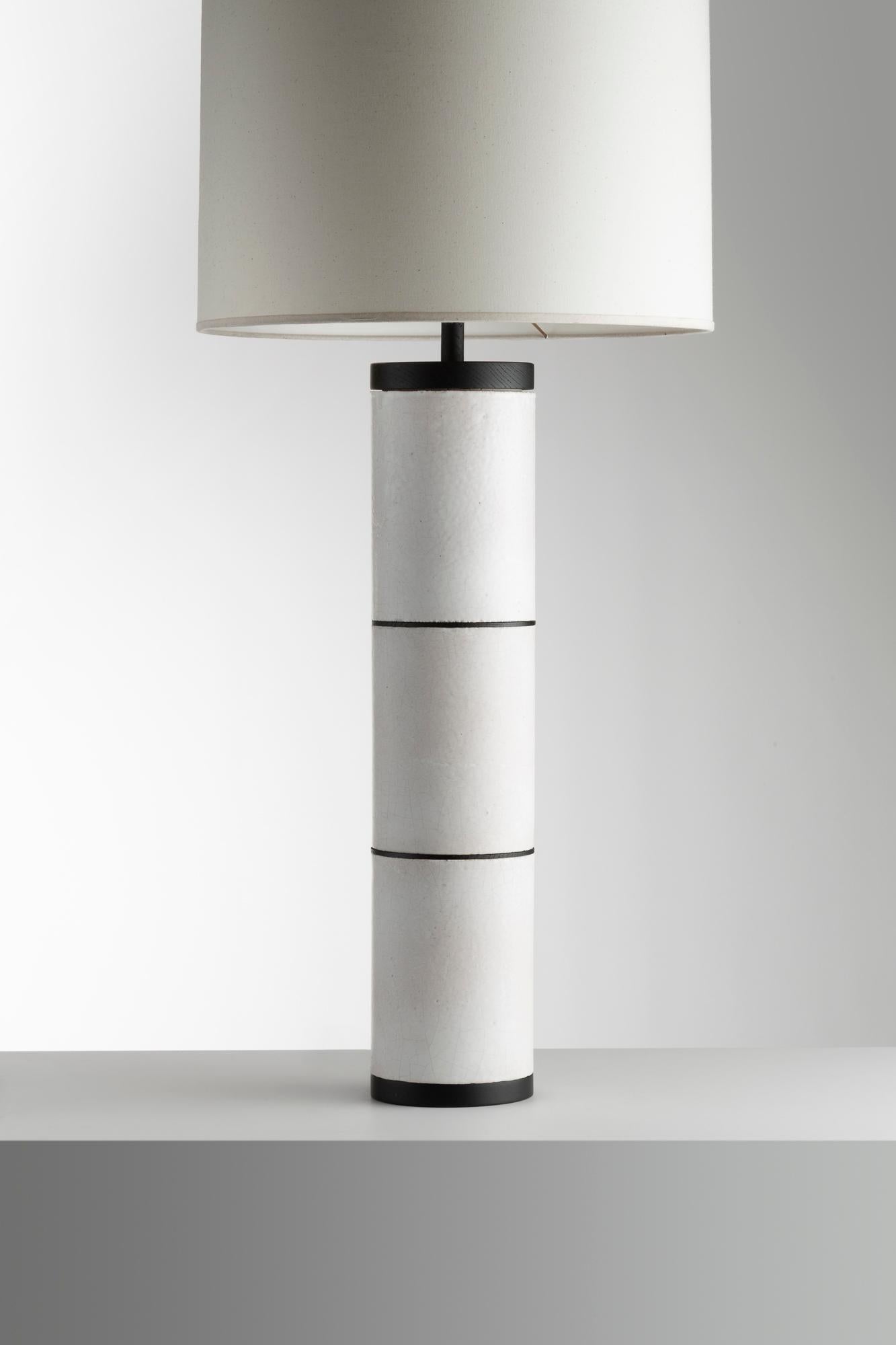 Esta lámpara de sobremesa de Gérard Simoen combina el rigor geométrico con una discreta elegancia. Con una base cilíndrica segmentada en tres secciones y rematada con una gran pantalla minimalista, la pieza refleja el refinado enfoque de Simoen