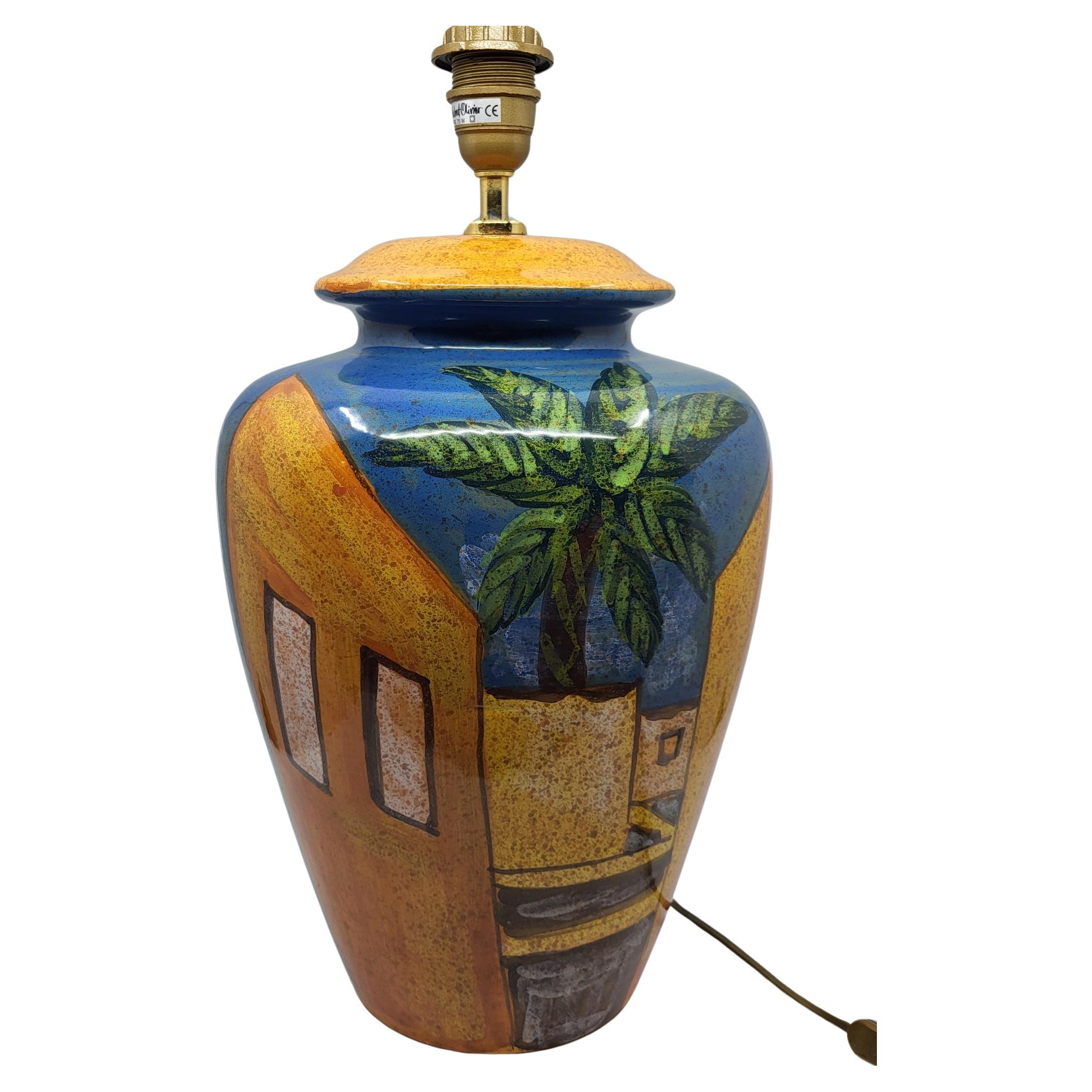 La très grande lampe de décoration du fabricant Hubert Olivier est bien plus qu'un simple éclairage ; elle est une véritable œuvre d'art. Fabriquée en céramique, cette pièce présente un décor captivant représentant une ville méditerranéenne,