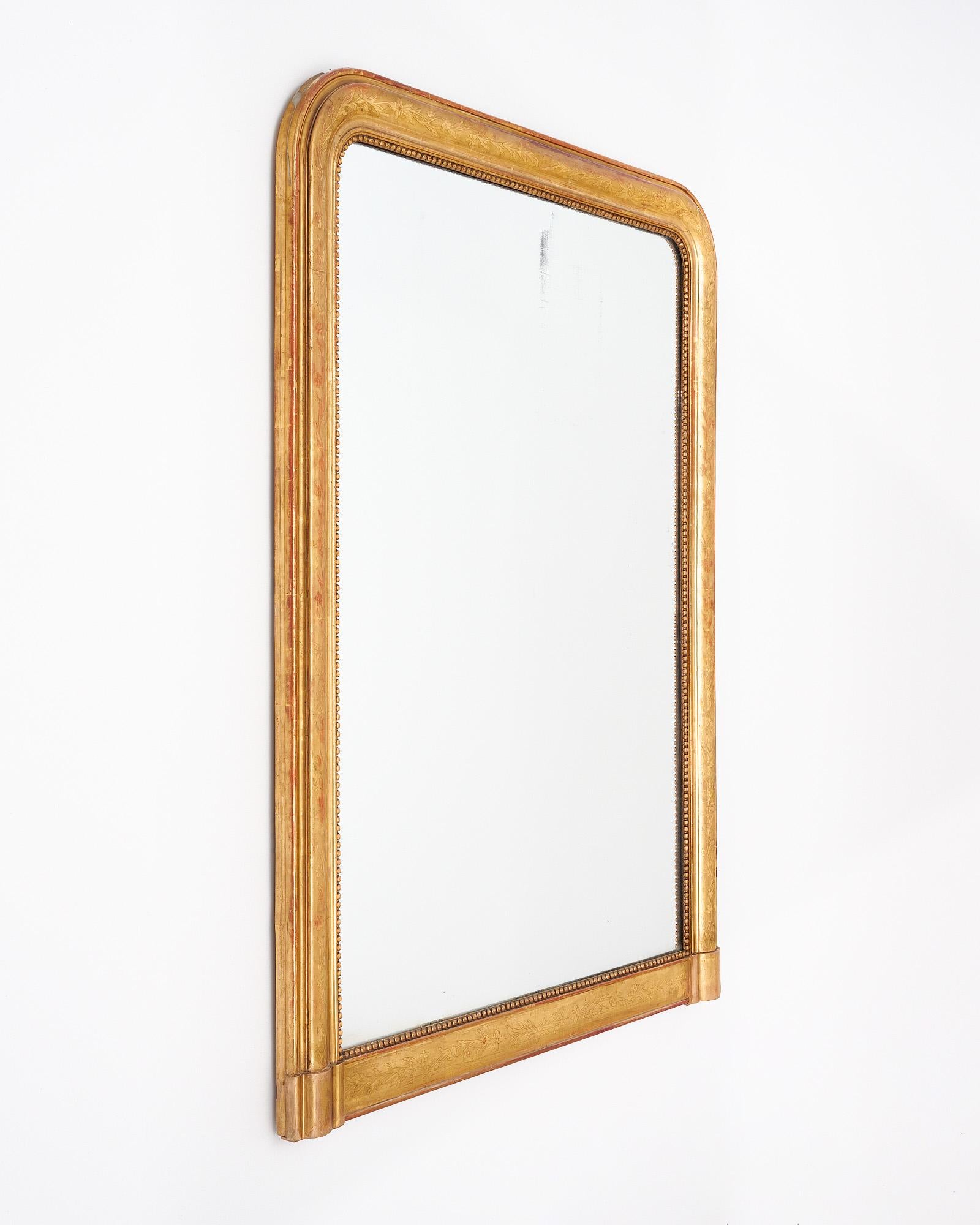Miroir de la période Louis Philippe en France. Ce miroir présente le miroir au mercure d'origine dans le cadre moulé classique de Louis Philippe avec des coins supérieurs incurvés. Le cadre est en bois massif sculpté, ciselé et stuqué à la main. Ce