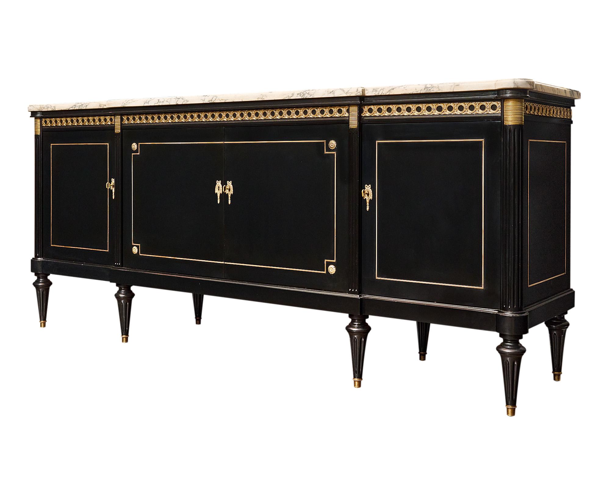 This French Buffet/Enfilade is a remarkable piece crafted in Paris, France, reflecting the elegant Louis XVI style. Made with care from Mahogany, it features four doors that open to reveal adjustable shelves and drawers. The exquisite ebony finish,