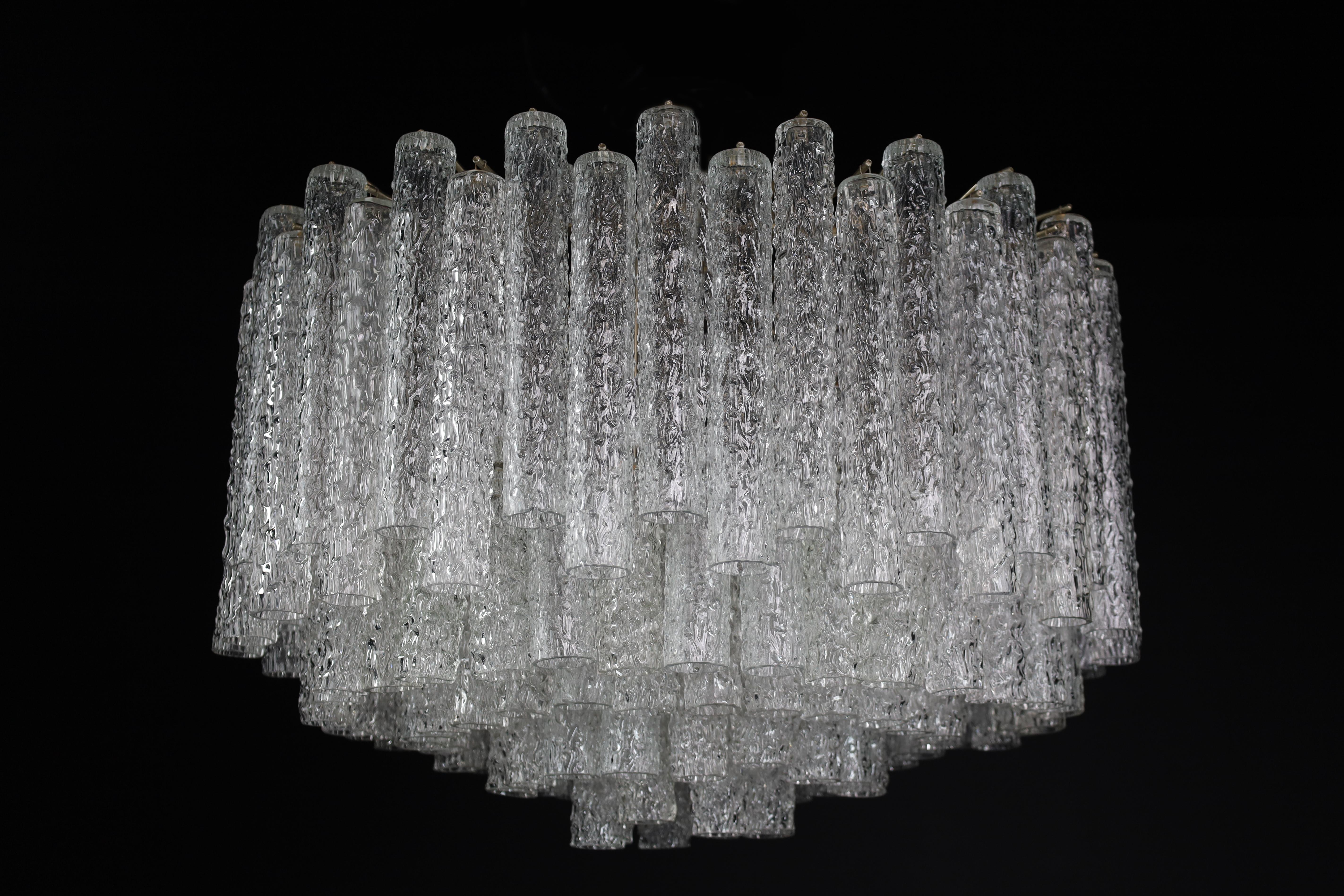 Grande midcentury chandelier designed by Venini with Murano glass, Italy 1950s

This grande chandelier consists of countless glass 'tubes' with textured designs of Murano glass and is mounted on a tiered metal frame. The sheets beautifully refract