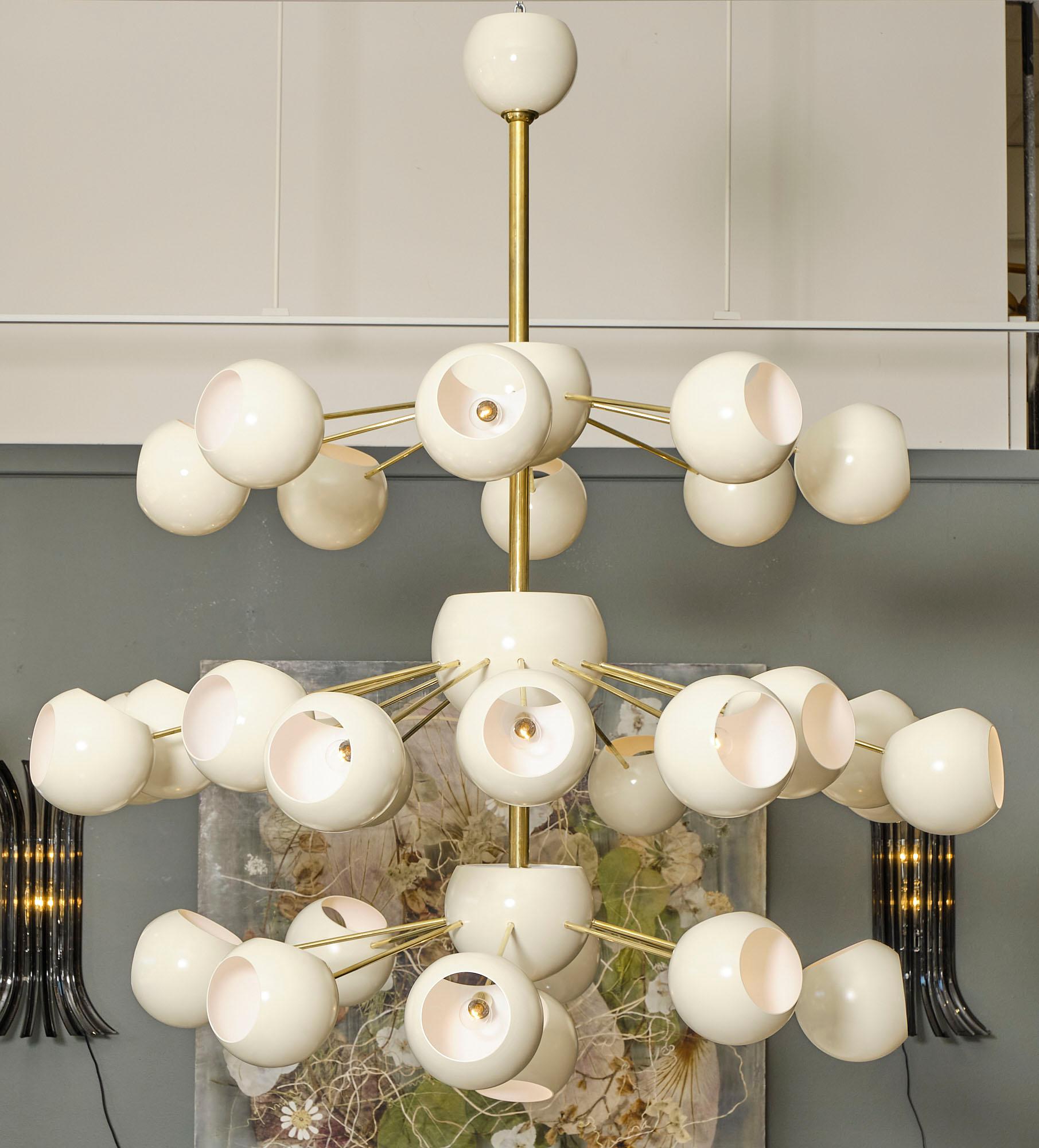 Lampadario italiano della regione Veneto con più elementi in acciaio laccato avorio.  orbite collegate con steli di ottone al corpo principale del pezzo. 
Questo lampadario è stato cablato di recente per soddisfare gli standard americani.