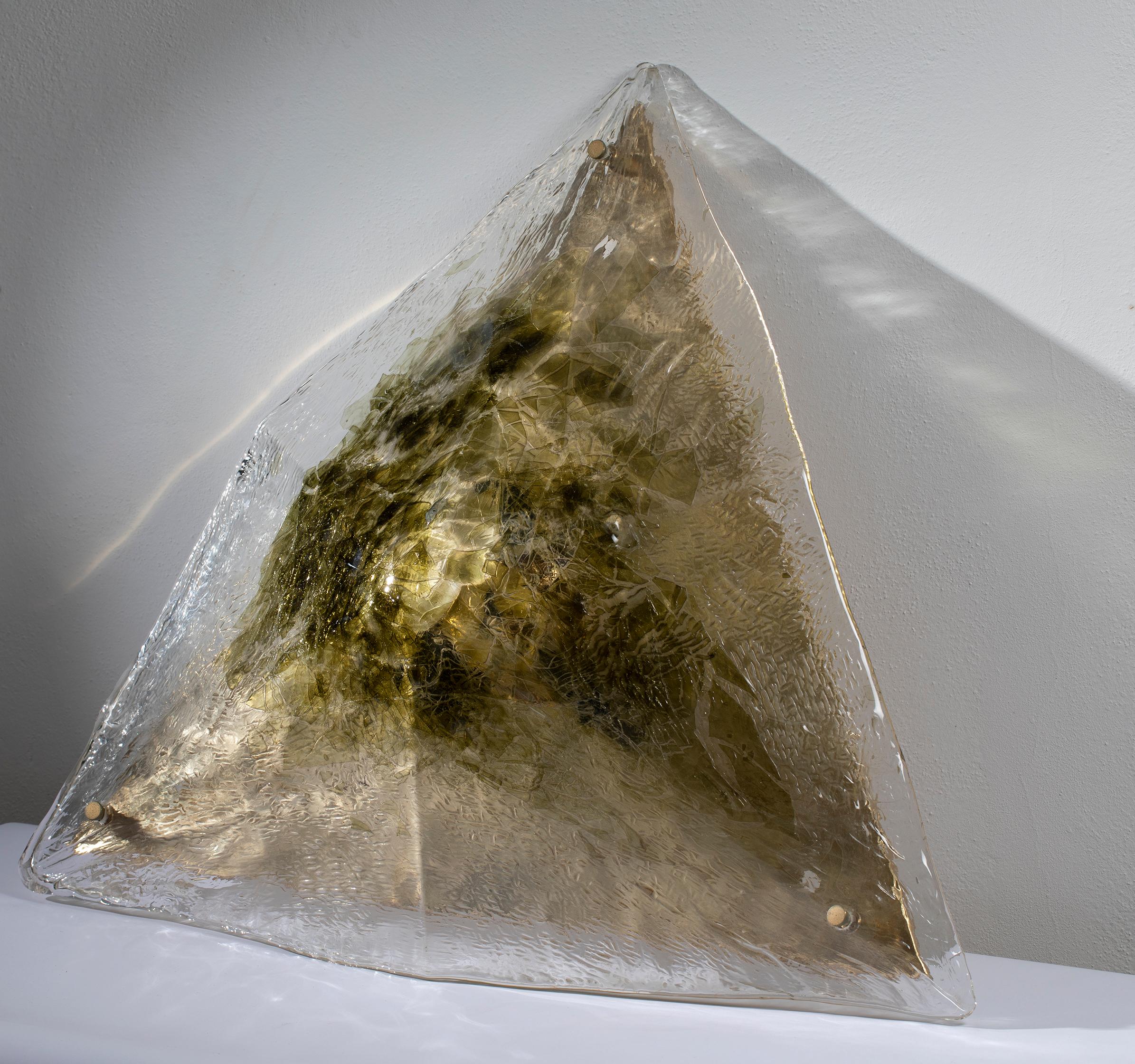 Grande plafoniera a forma piramidale, prodotta da La Murrina negli anni 70, in vetro di Murano con inclusioni nei toni del verde e del giallo ambra. L’attacco al soffitto è una grande piastra in ottone, visibile in foto. L’impianto elettrico è coevo