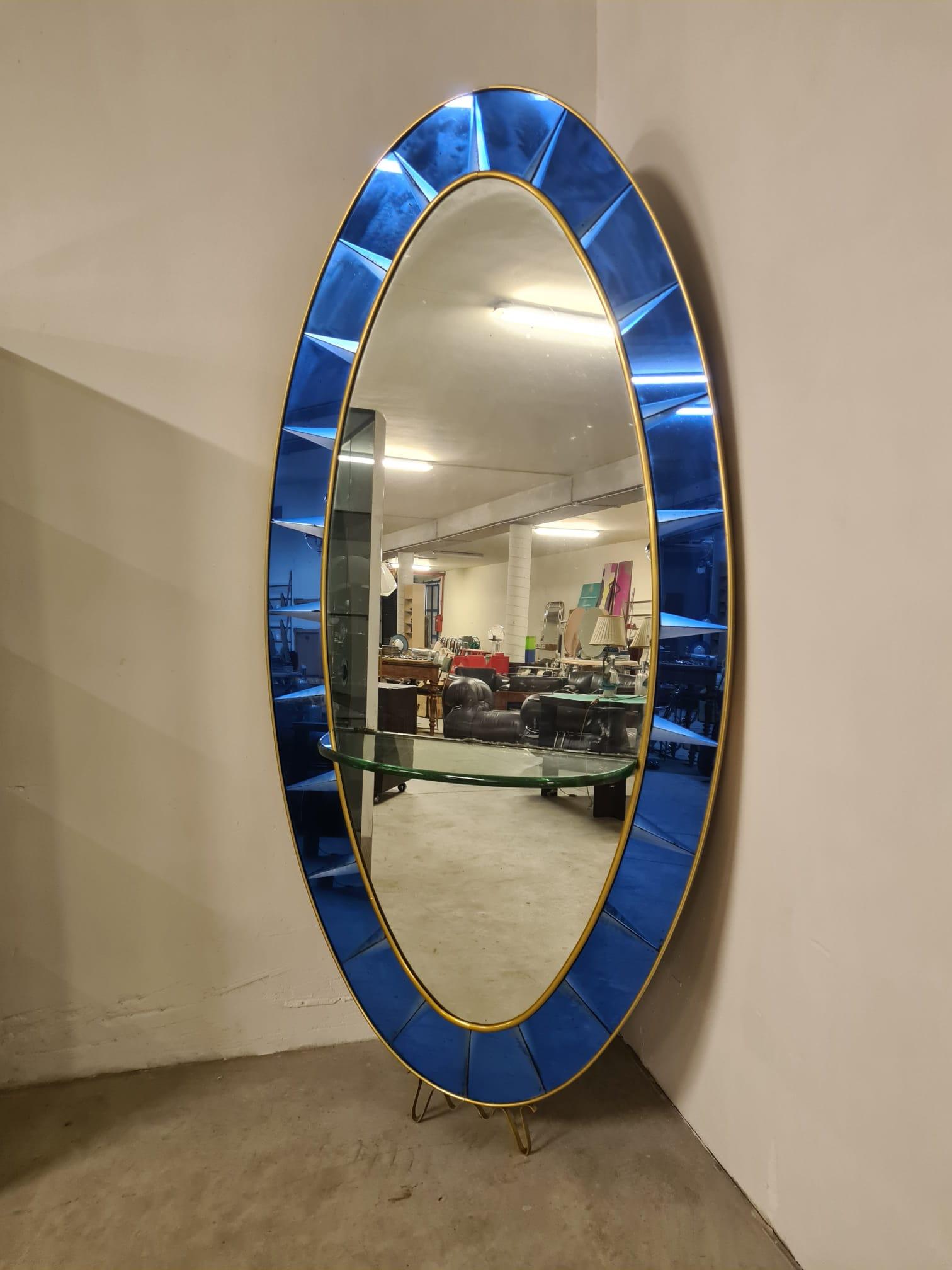 Cristal Art mirror with shelf

Large mirror produced in the 1950′s by Cristal Art

Oval in shape with brass crown feet and brass edging.

Mercury and blue ground mirrored glass frame and central mercury mirrors.

Central semicircle shelf made of