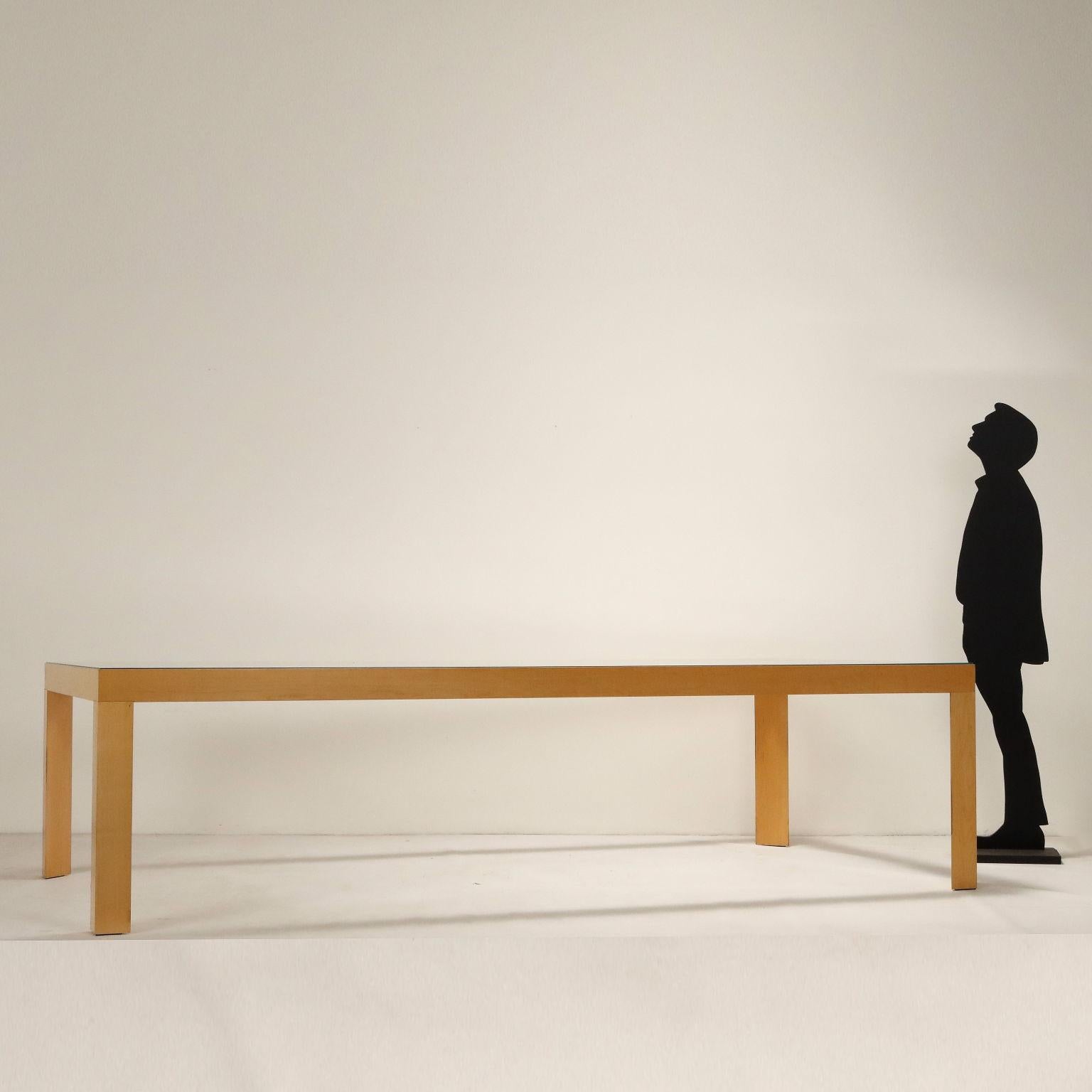 Grande tavolo con struttura in alluminio effetto legno, piano in vetro trasparente. 