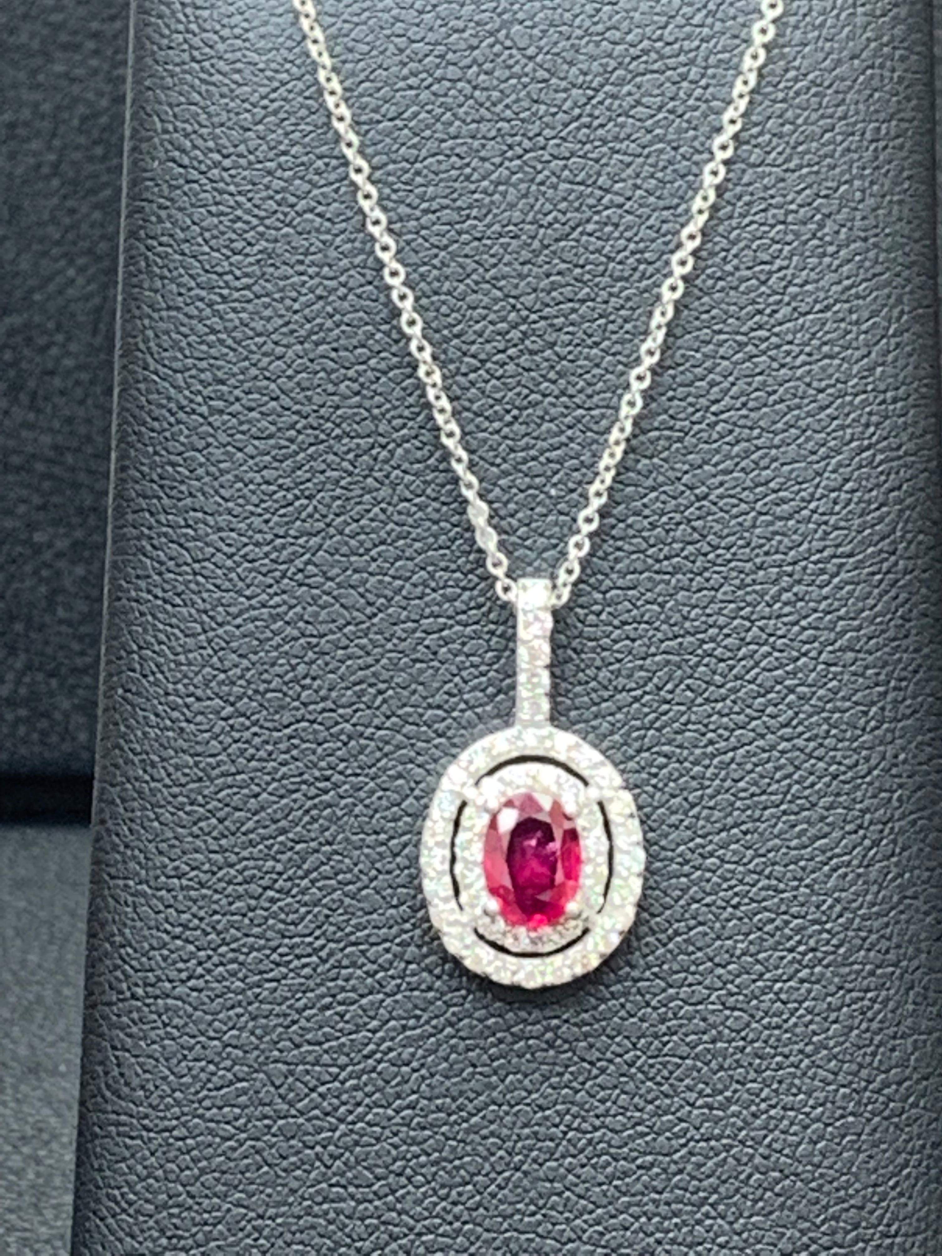 A floral motif pendant necklace showcasing a 0.81 carat oval ruby, surrounded by a single row of 35 round brilliant diamonds weighing 0.37 carat . Set in 14 karat white gold. 18