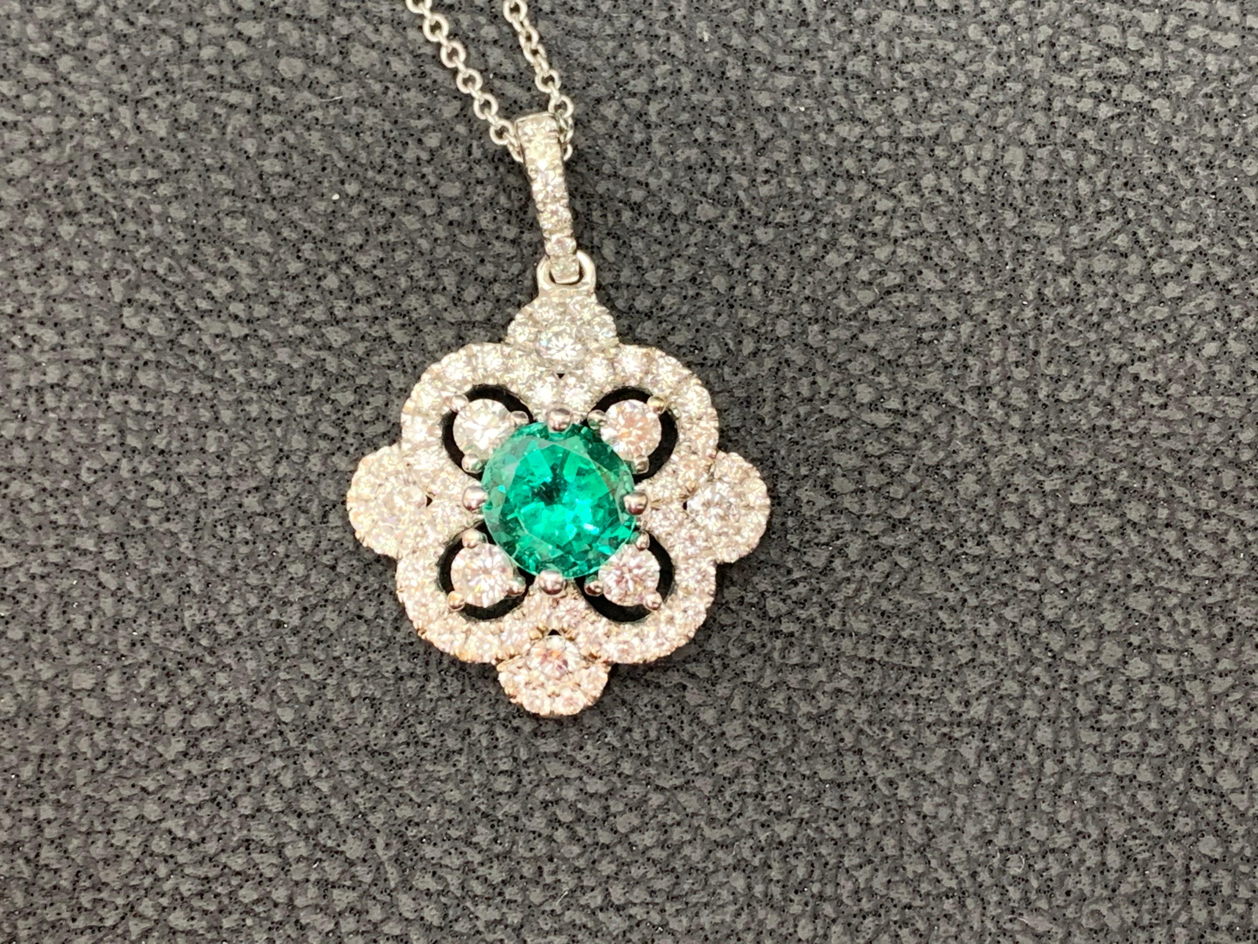 Set with a round green emerald center stone accented by 4 round shape brilliant diamonds on each corner. Each 4 diamonds are set in an open work semi-circles set with Diamonds. Finished with another open-work design with diamonds. Weight of diamonds