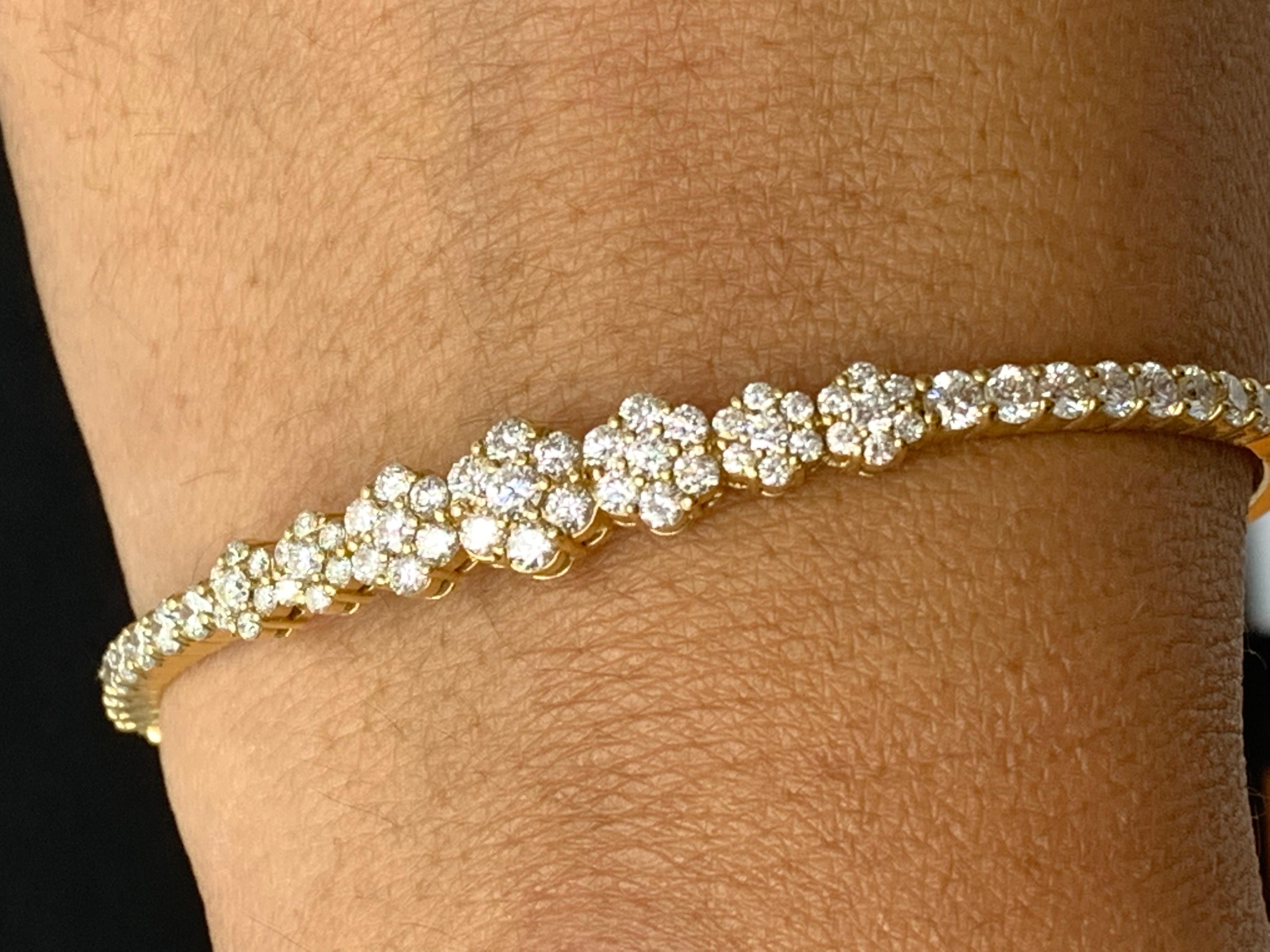 Sparkle in the spotlight with this diamond bangle bracelet. Brilliant cut Diamond flowers graduating towards the center weigh 2.54 carat in total. Set in a 14k yellow gold basket. A hinged design bracelet for easy wear and removal. 

All diamonds