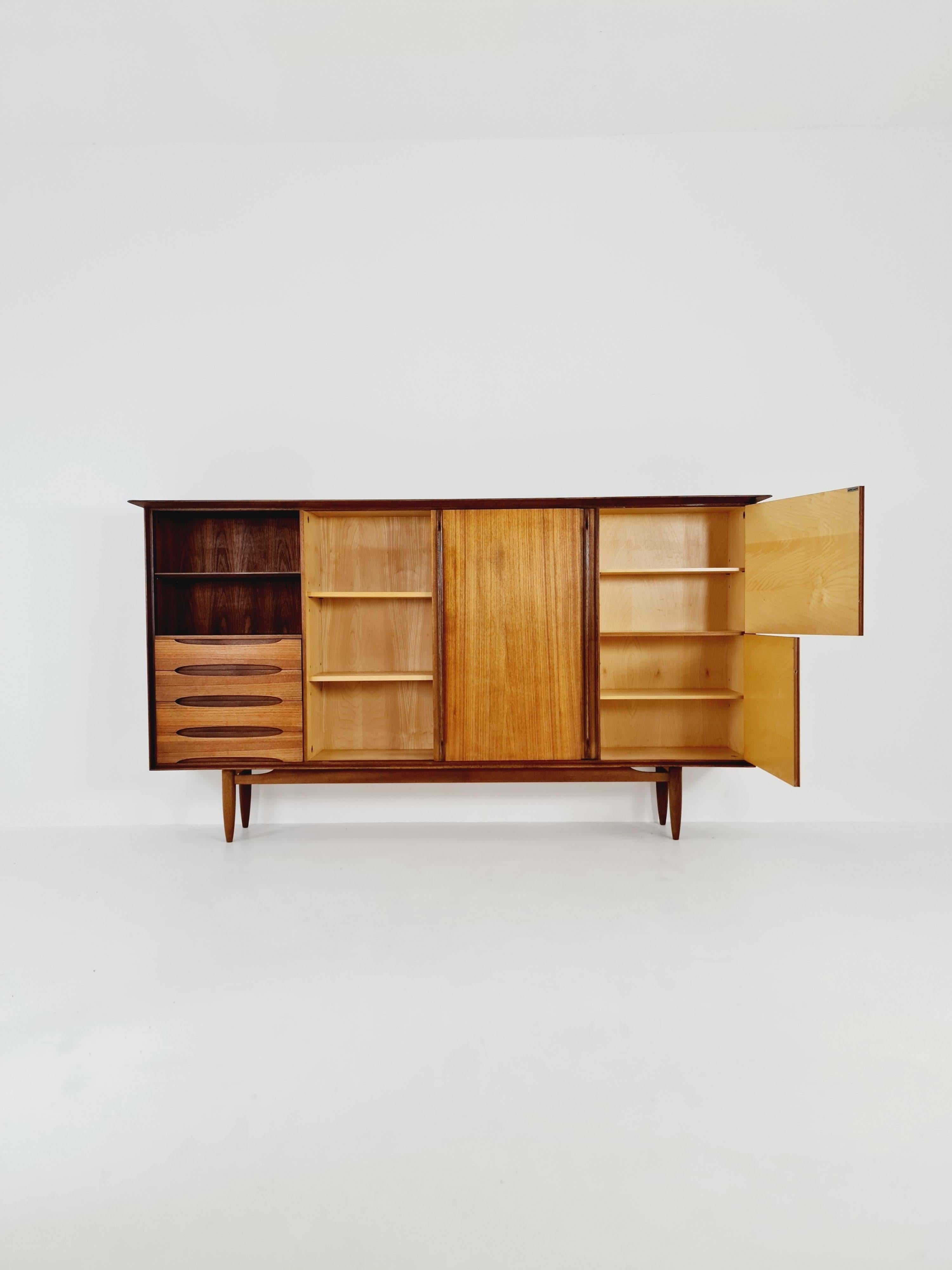 The high-quality highboard was produced by the manufacturer Omnia in the 1960s.

The furniture was designed in terms of dimensions and layout for plenty of storage space and offers plenty of space with three cupboard parts, the bar compartment and