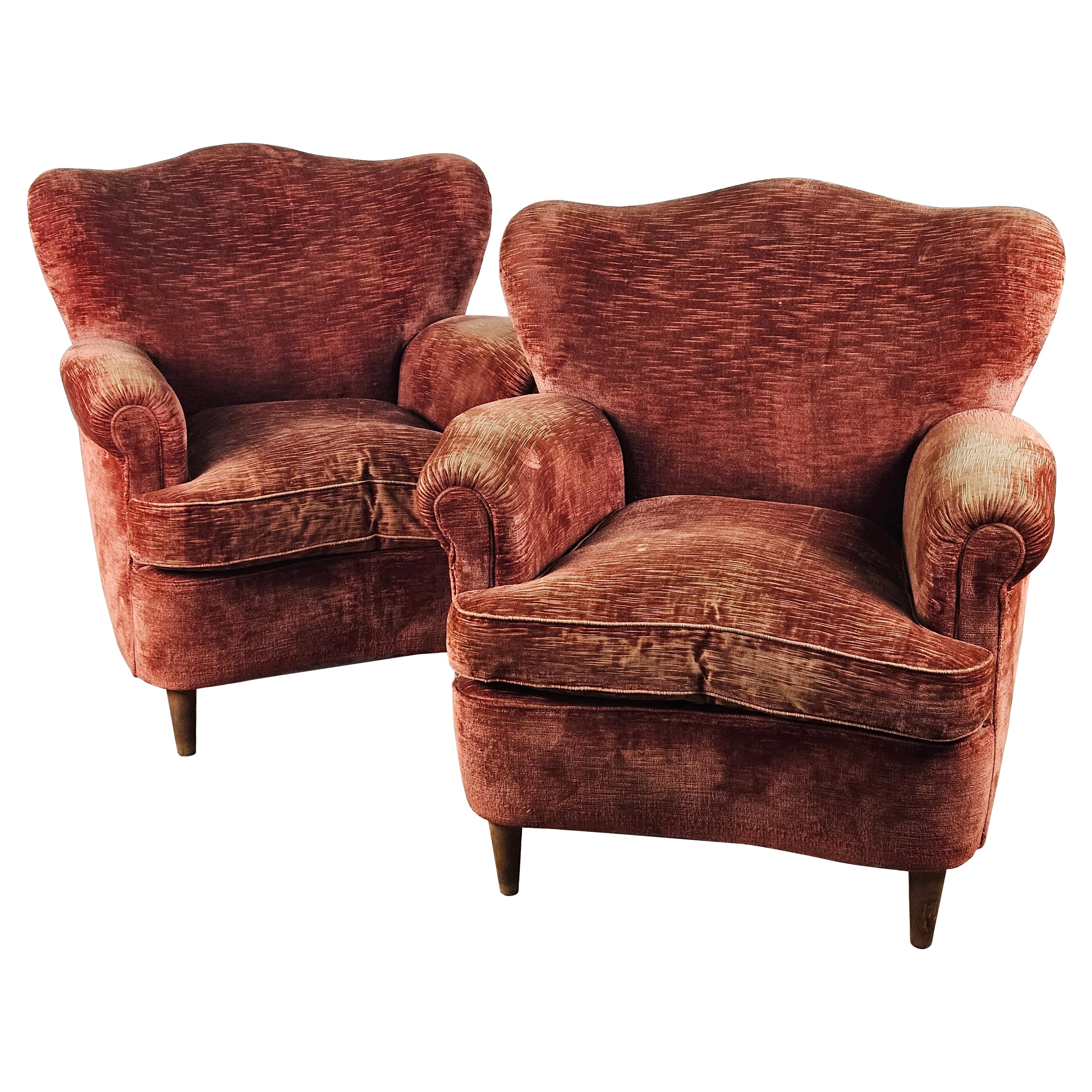 Large 1950s armchairs upholstered in red fabric with wooden feet