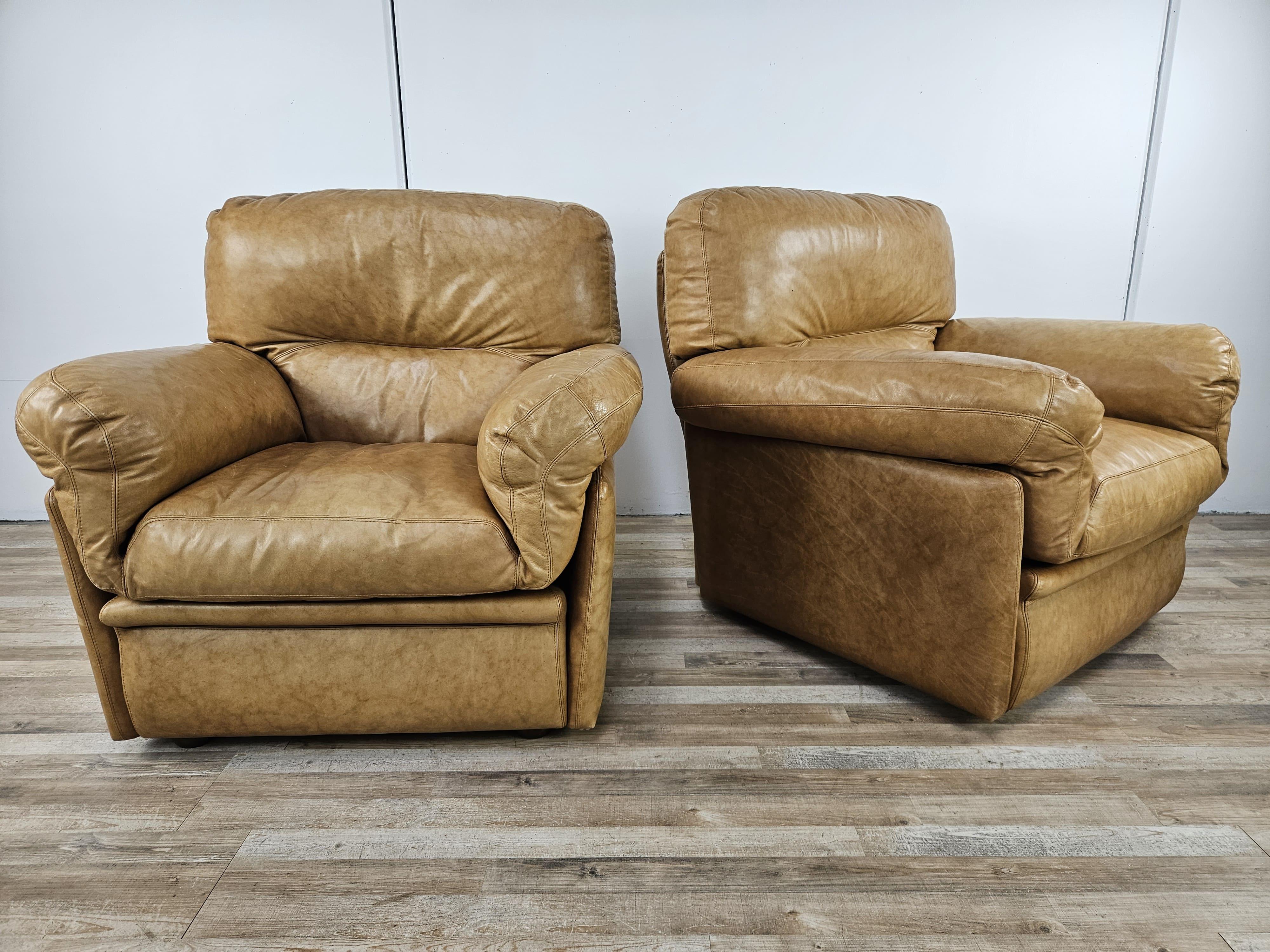 Paire de grands fauteuils en cuir de couleur camel du début des années 1970, de fabrication et de qualité italiennes.

Les coussins du dessous sont tous déhoussables et amovibles, les coussins d'assise sont fixés au moyen de boucles en
