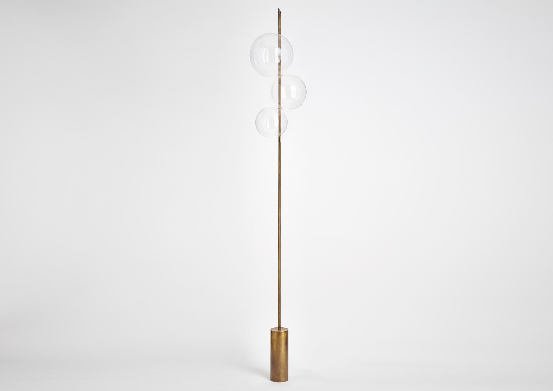 Grandine Three Lights s ist eine minimalistische, zeitgenössische Stehleuchte, die von Hagelkörnern inspiriert ist. Sie besteht aus drei sich berührenden, mundgeblasenen Glaskugeln, die so angeordnet sind, dass sie den Eindruck von Eiskugeln